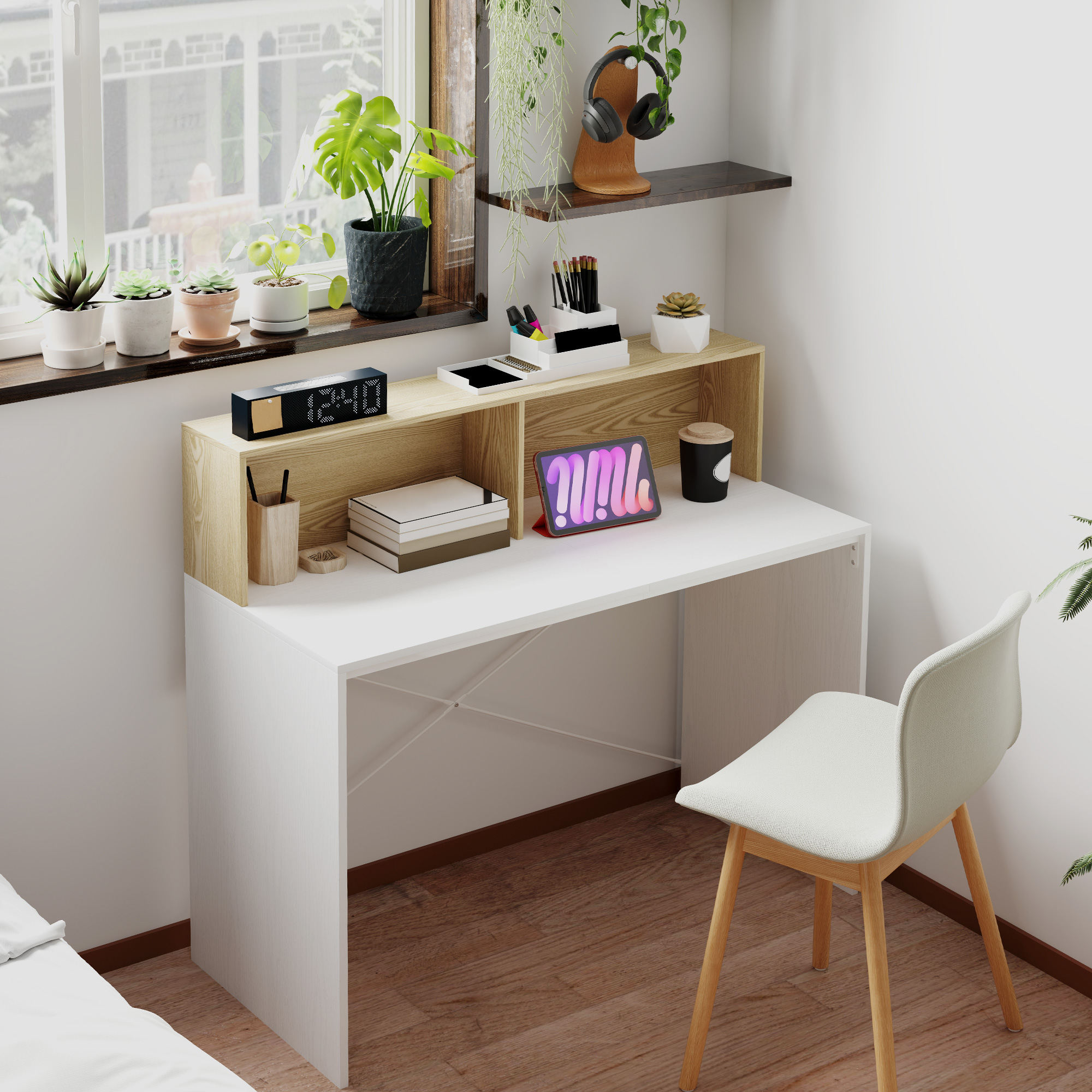 Un escritorio blanco con una tableta, material de oficina y plantas junto a la ventana.