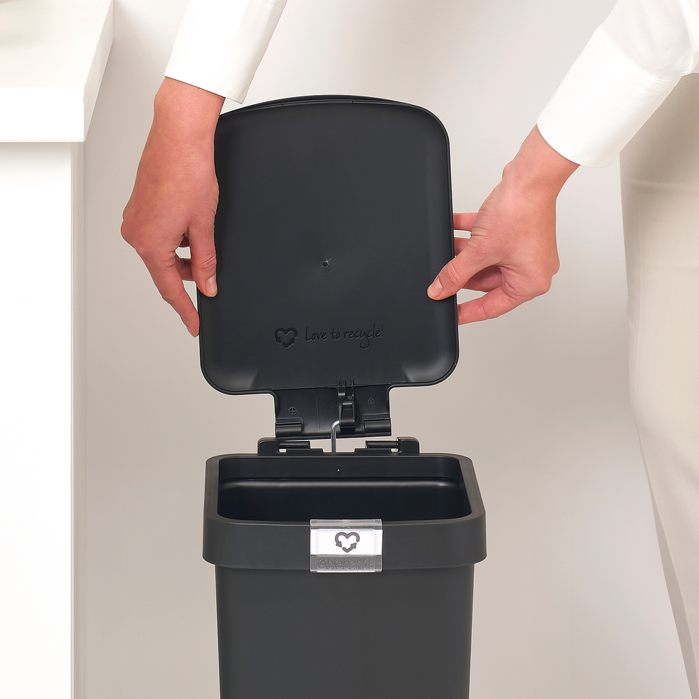 Handen openen zwarte prullenbakdeksel met "Love to recycle!".