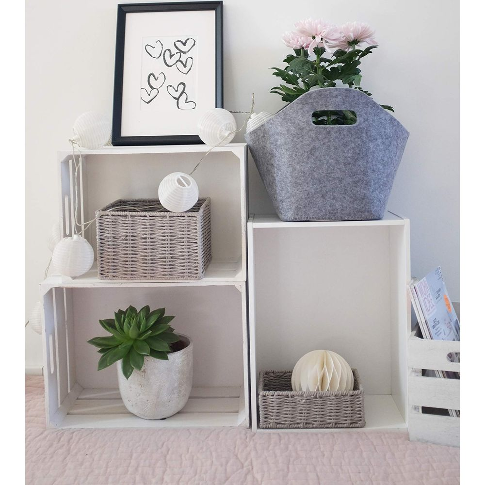 Ein Regal mit Dekoartikeln: Bilder, Körbe, Pflanze, Blumen und Lichterketten.