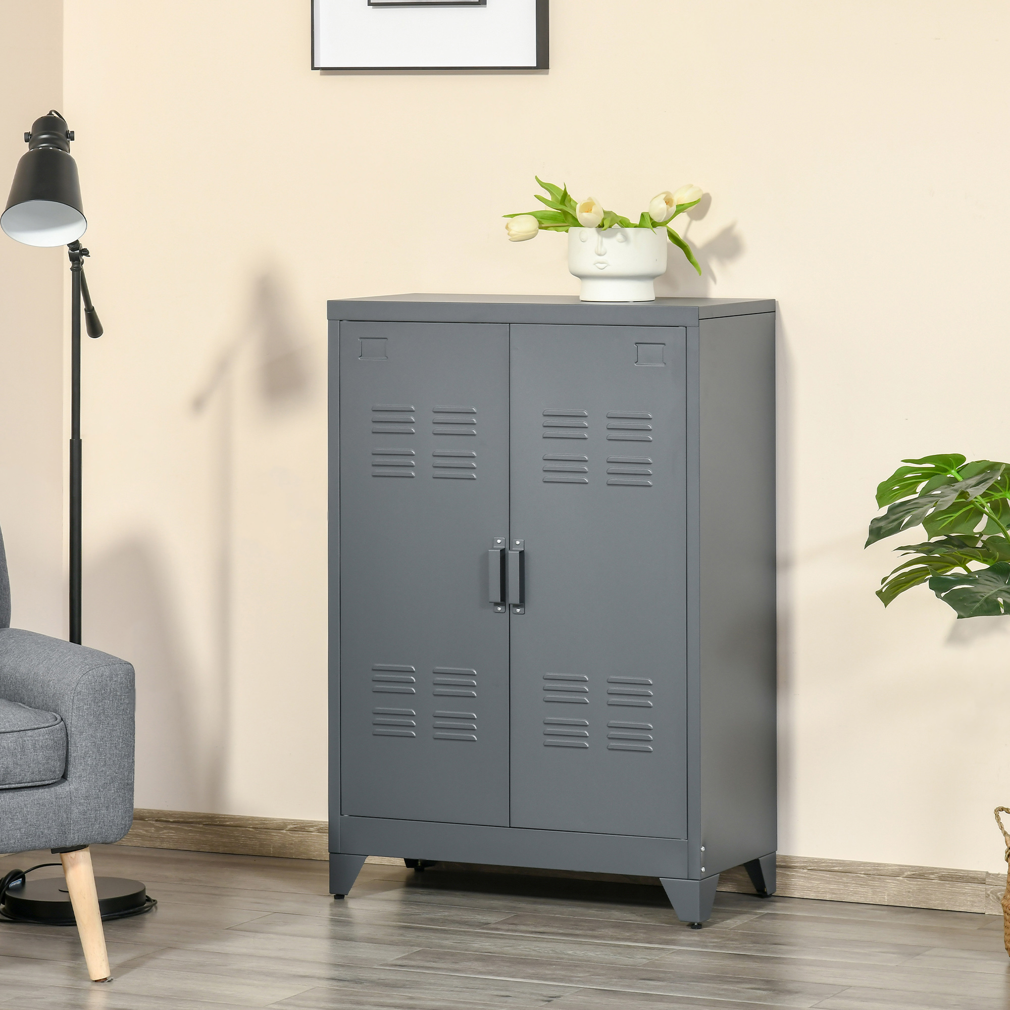 Un armario metálico gris con dos puertas está en una habitación. A la izquierda hay una silla y una lámpara.