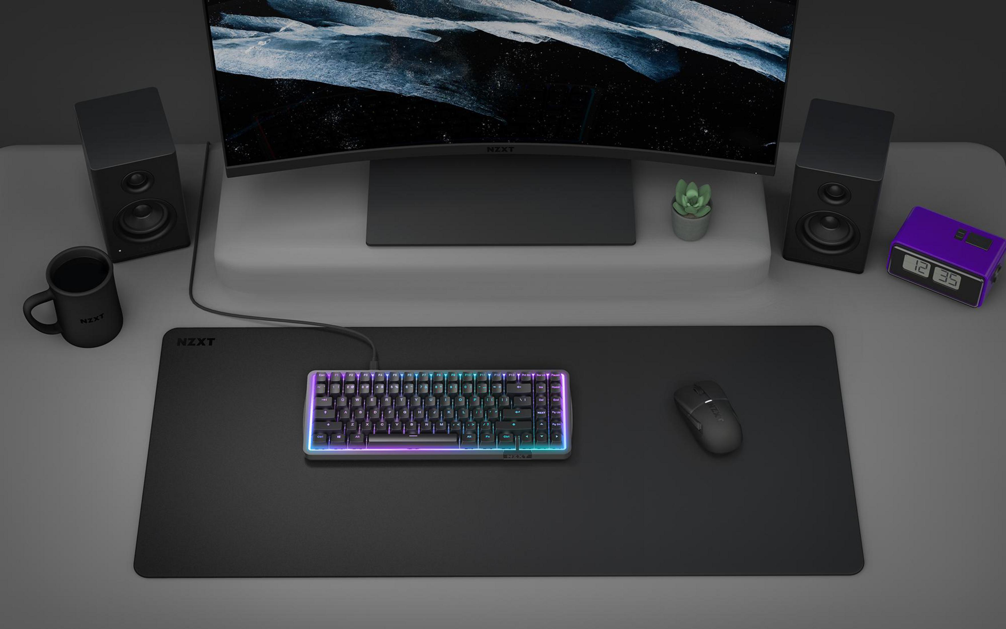 Ein Schreibtisch mit Tastatur, Maus, Lautsprechern, Tasse und einem Monitor.