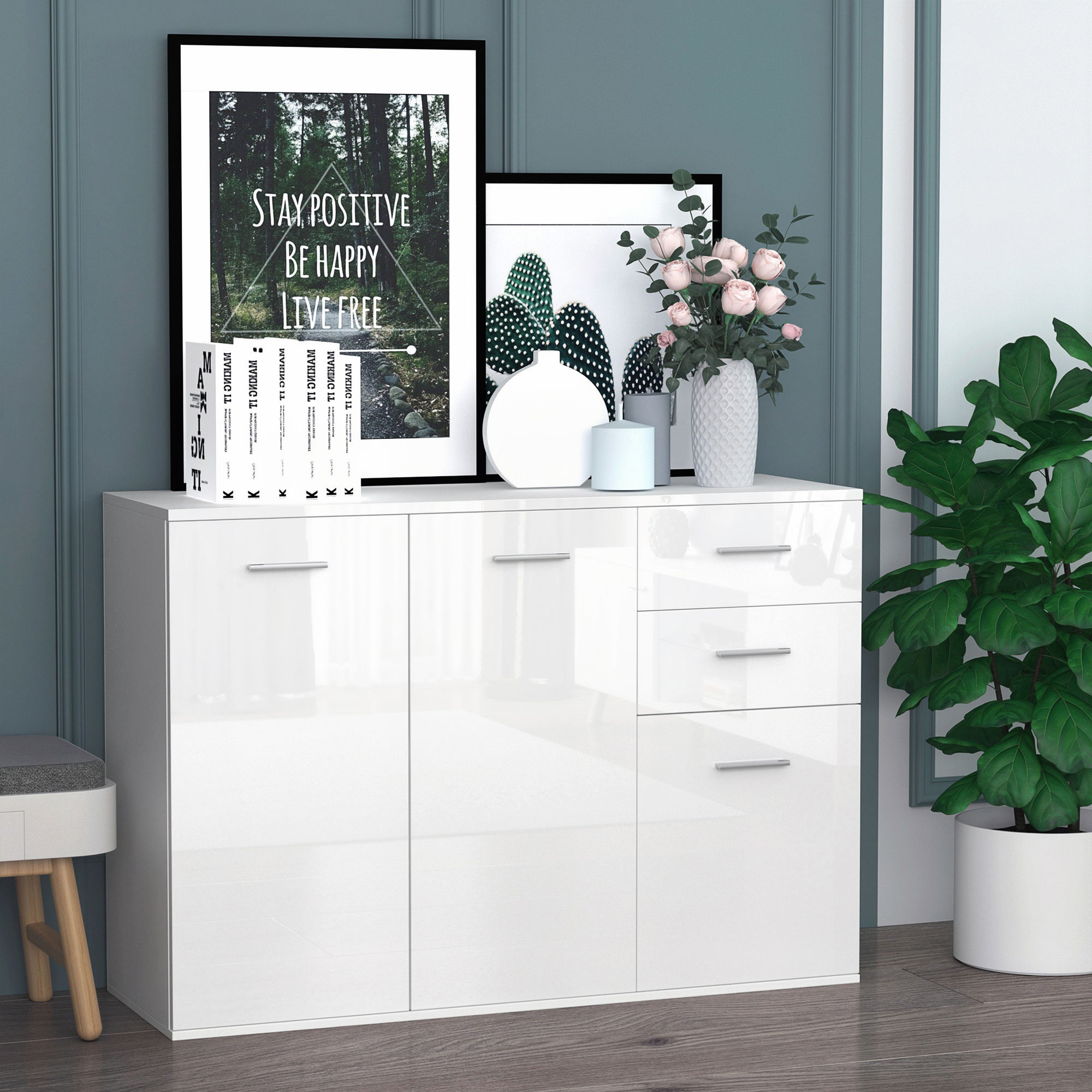 Aparador blanco con arte enmarcado, jarrones, libros y una planta.