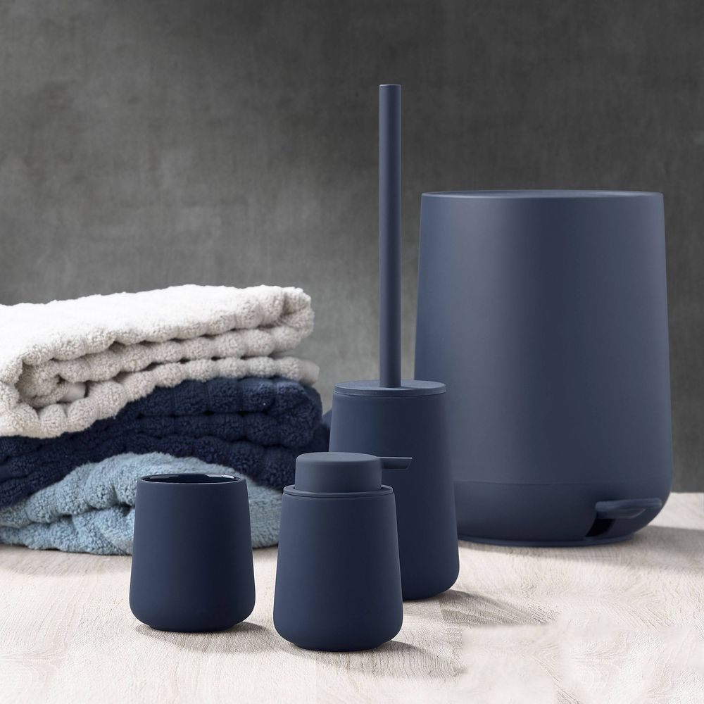 Dunkelblaue Badaccessoires: Seifenspender, Becher, Bürste, Mülleimer, Handtücher.