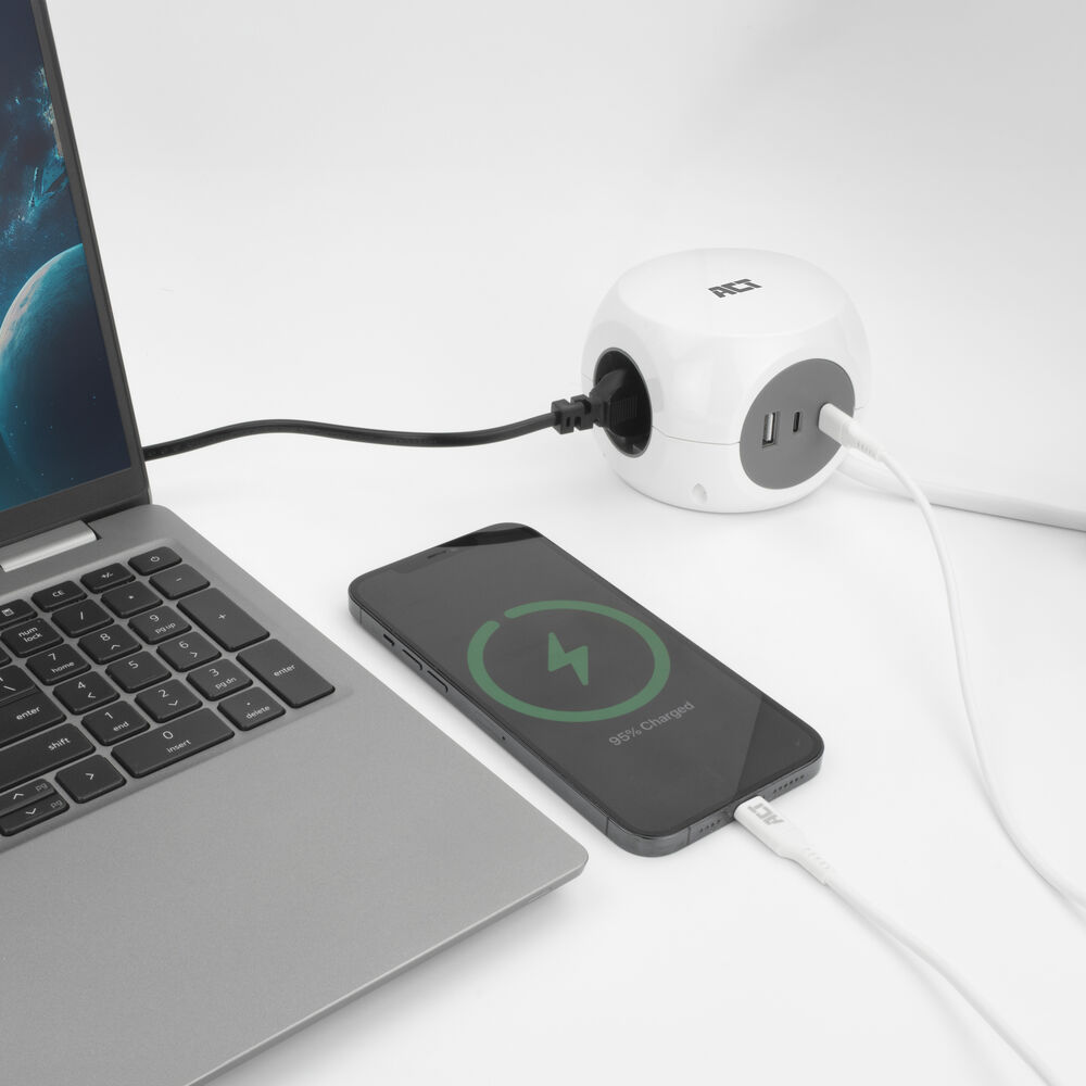 A laptop, a smartphone, and a white cube charger on a white surface.