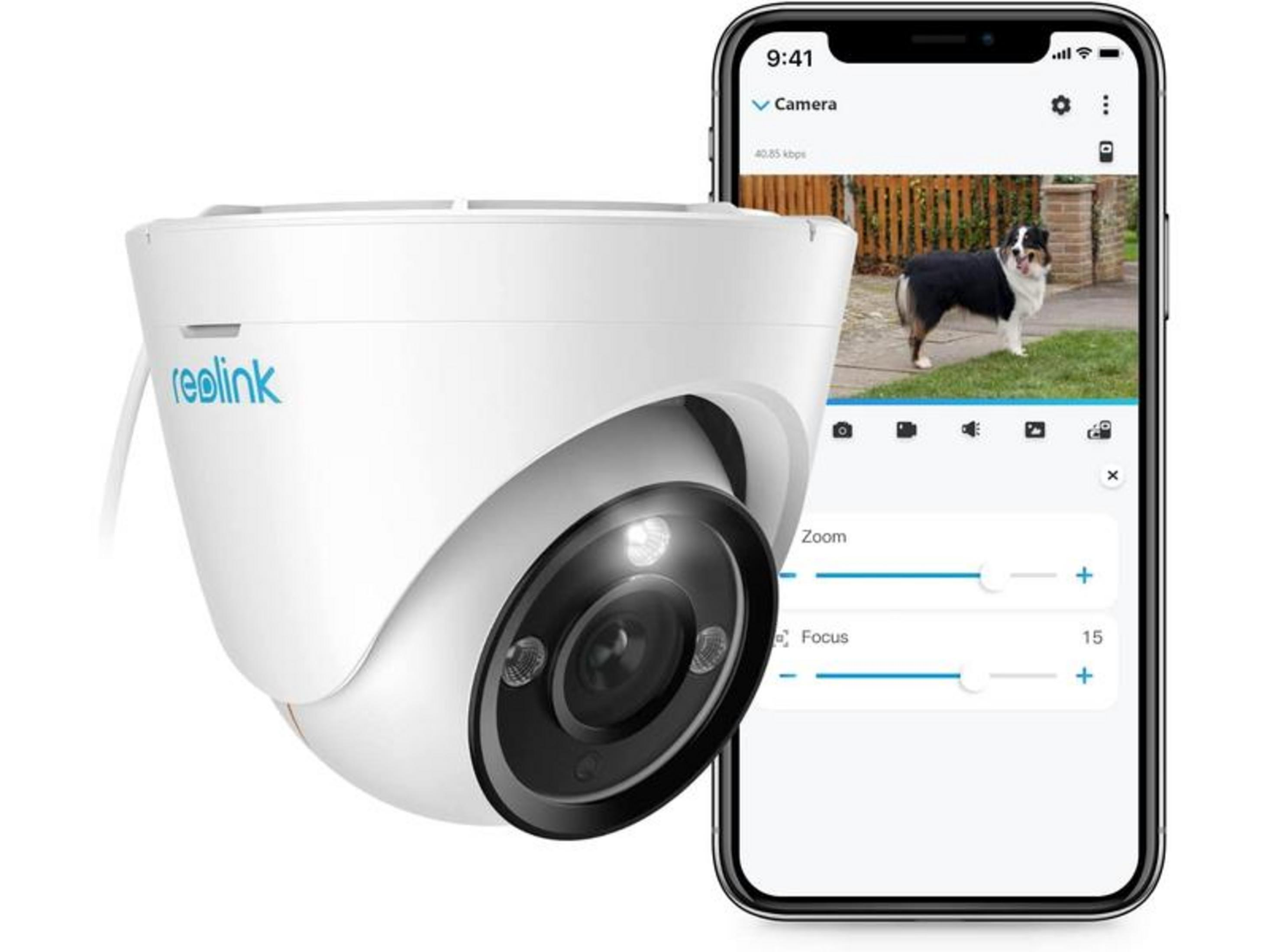 Une caméra de sécurité blanche à côté d'un smartphone affichant un chien en extérieur.
