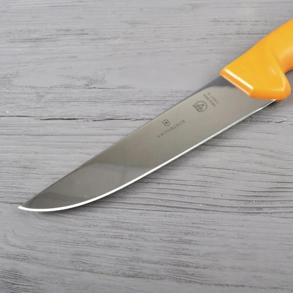 Turuncu saplı bir Victorinox bıçağı ahşap yüzeyde duruyor.