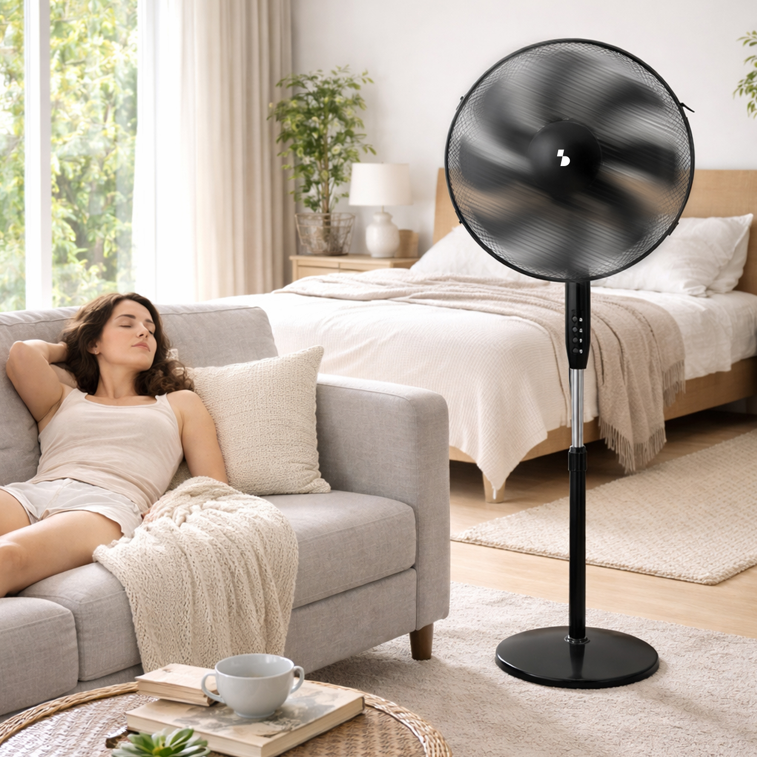 Una donna si riposa su un divano mentre un ventilatore nero è in funzione sullo sfondo.