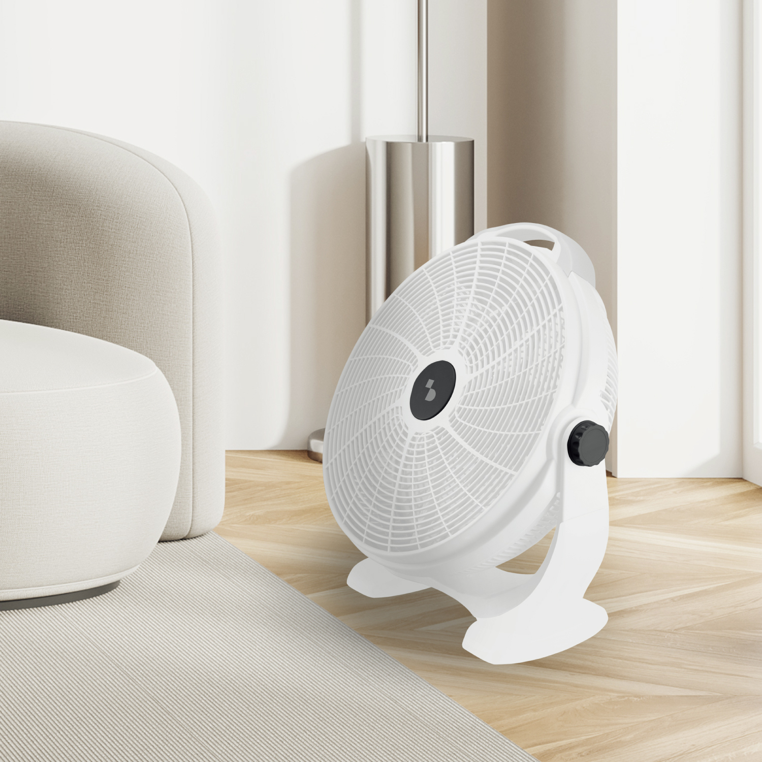 Un ventilatore bianco si trova su un pavimento in legno accanto a un divano chiaro.