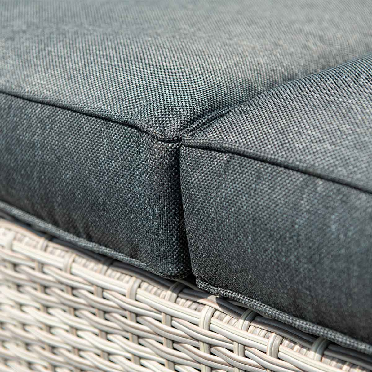 Coussins gris sur un canapé en osier de rotin gris clair.