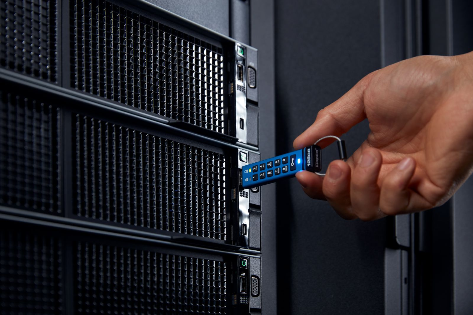 Hand steckt blauen USB-Stick mit Ziffernblock in Server.
