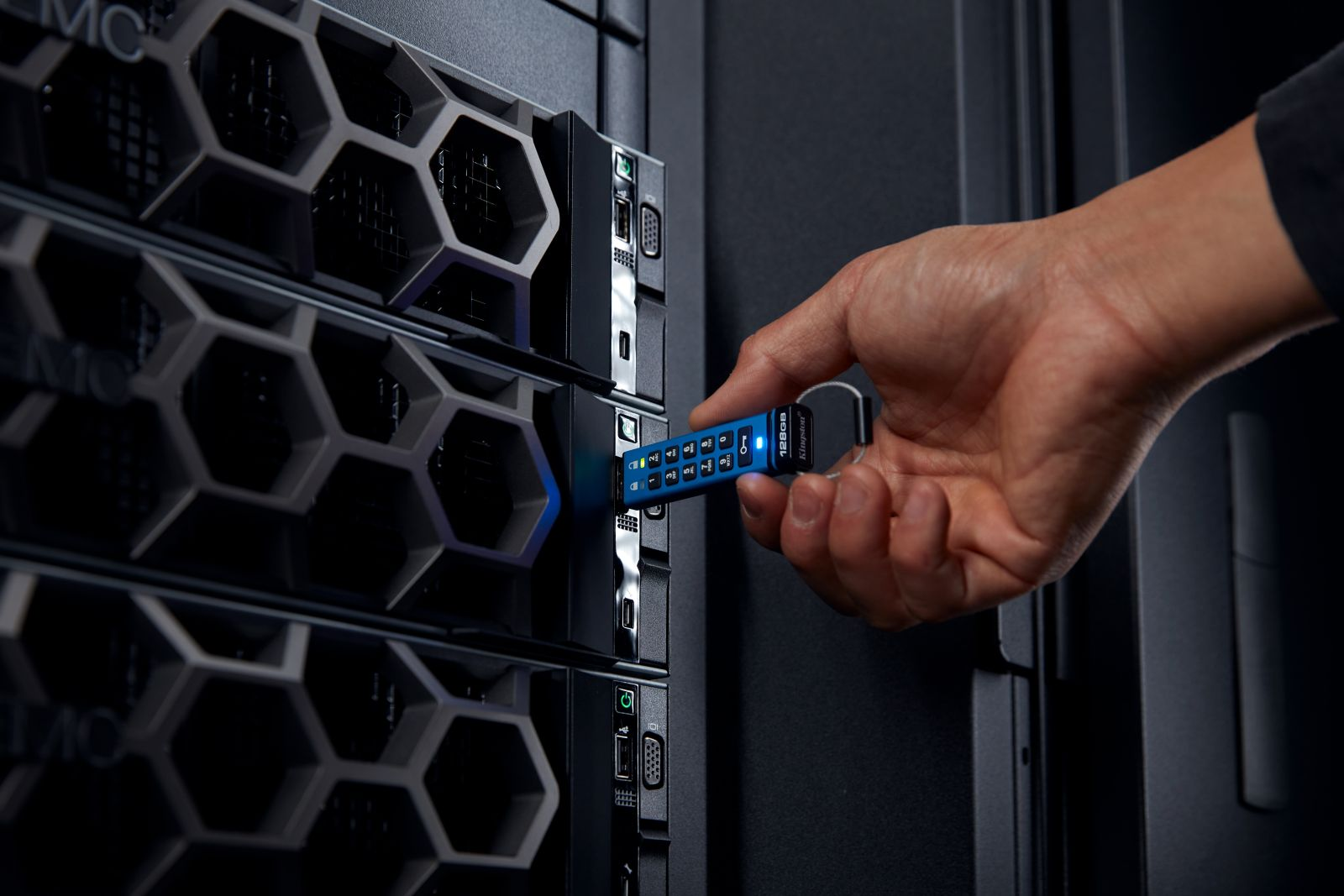 Ein Mann steckt einen blauen USB-Stick mit Tasten in ein Servergehäuse.