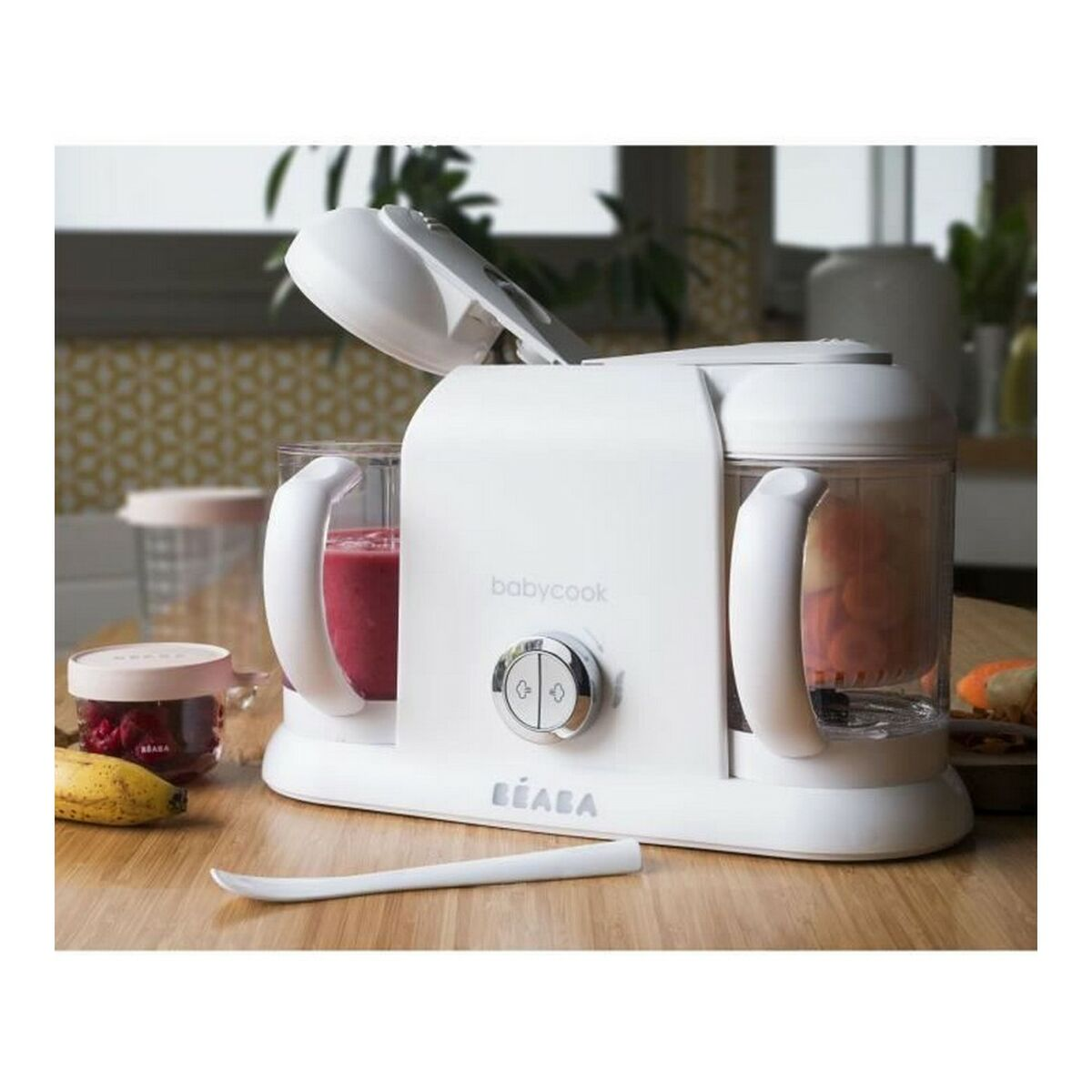 Ein weißer Baby-Food-Maker mit roten Beeren, Karotten und Banane auf einem Holztisch.