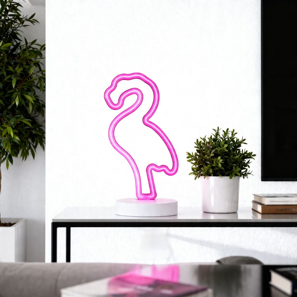 Een roze neon flamingo lamp staat op een plank naast een plant.