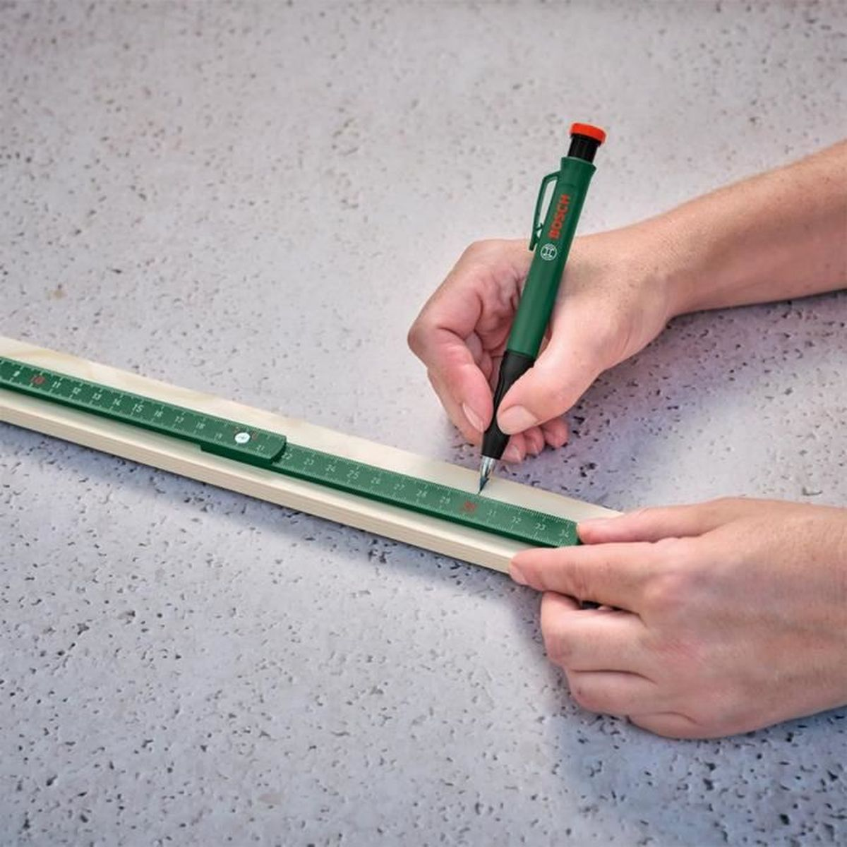Person markiert Holz mit Bleistift und Lineal.
