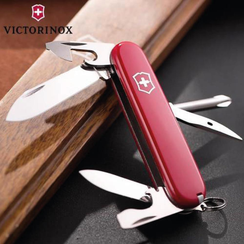 Kırmızı bir Victorinox İsviçre çakısı, bıçakları ve aletleri açık şekilde koyu bir yüzeyde duruyor.