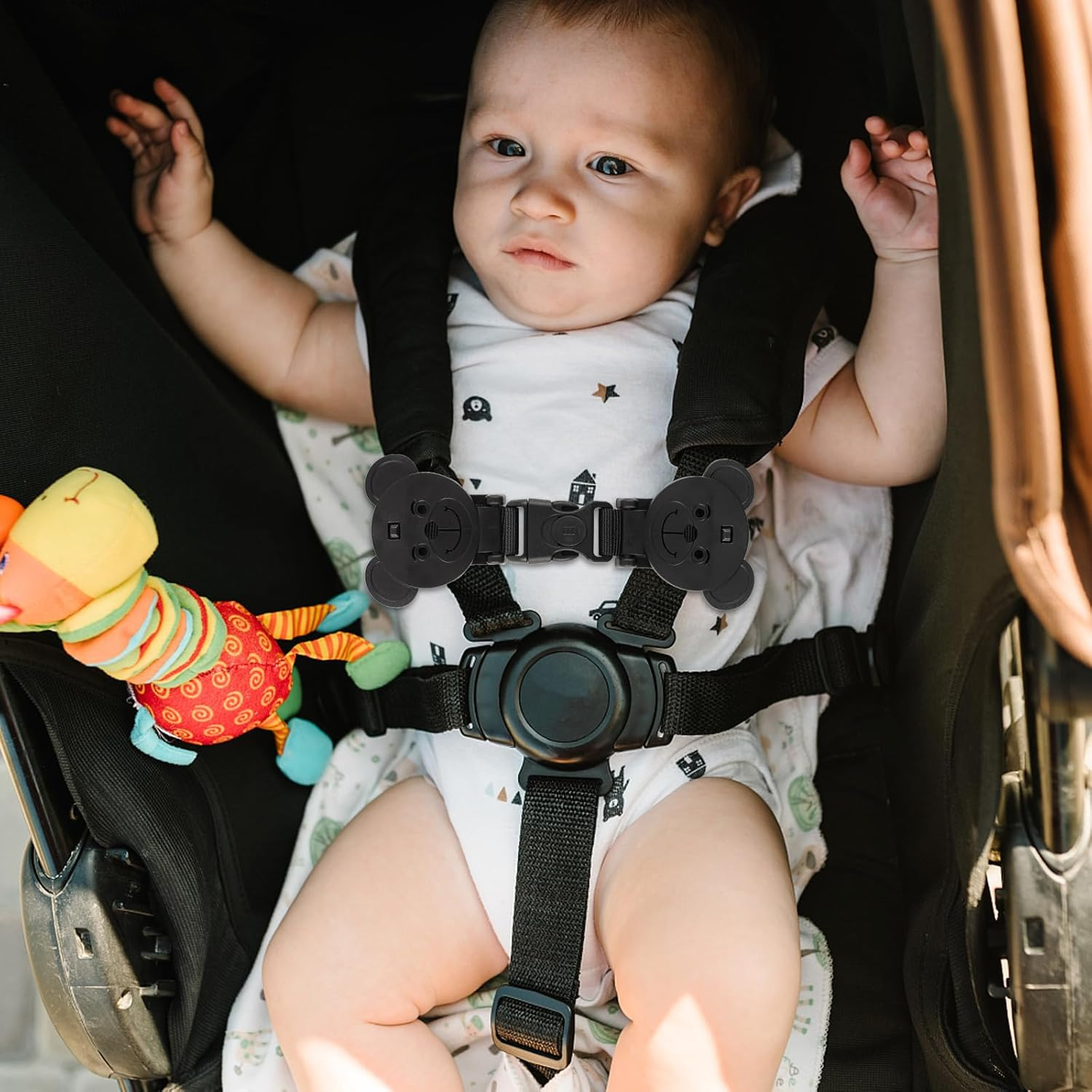 Ein Baby liegt im Kinderwagen mit Teddybär-Spielzeug und 5-Punkt-Gurt.