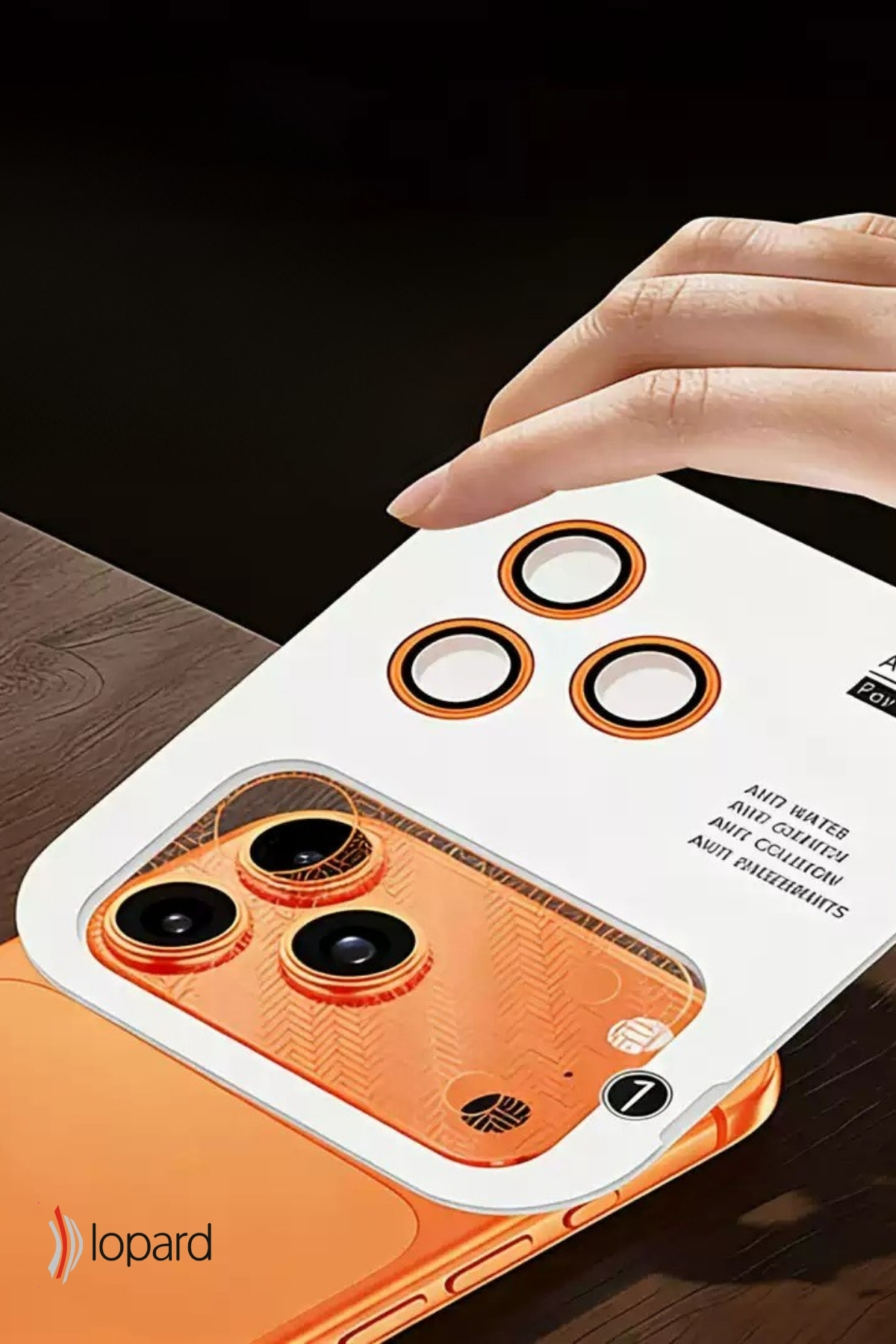 Üç lensli turuncu bir telefon kamerası için ekran koruyucu tutan bir el.
