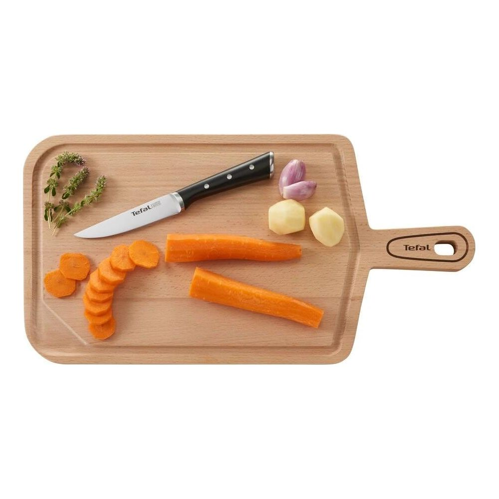 Tabla de cortar de madera con cuchillo, zanahorias, patatas, ajo y hierbas.