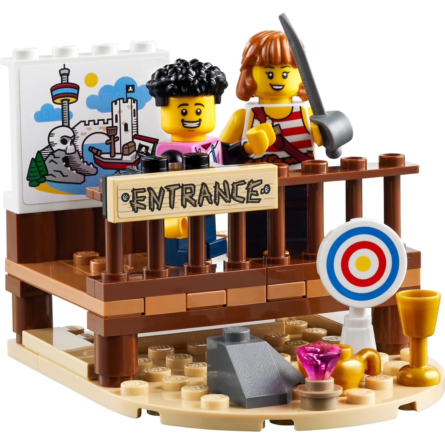 İki Lego figürü giriş tabelasının yanında duruyor, hedef tahtası ve hazineler yakın.