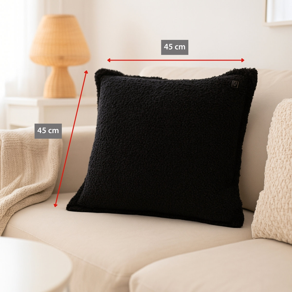 A black, fluffy cushion, 45x45cm, is placed on a beige sofa.
