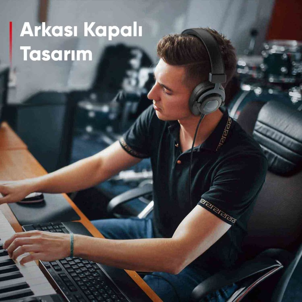 Kulaklıklı adam kayıt stüdyosunda klavye çalıyor.