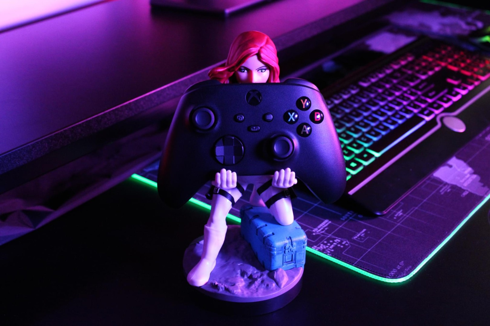 Una statuetta tiene un controller Xbox davanti a una tastiera e tappetino illuminati.