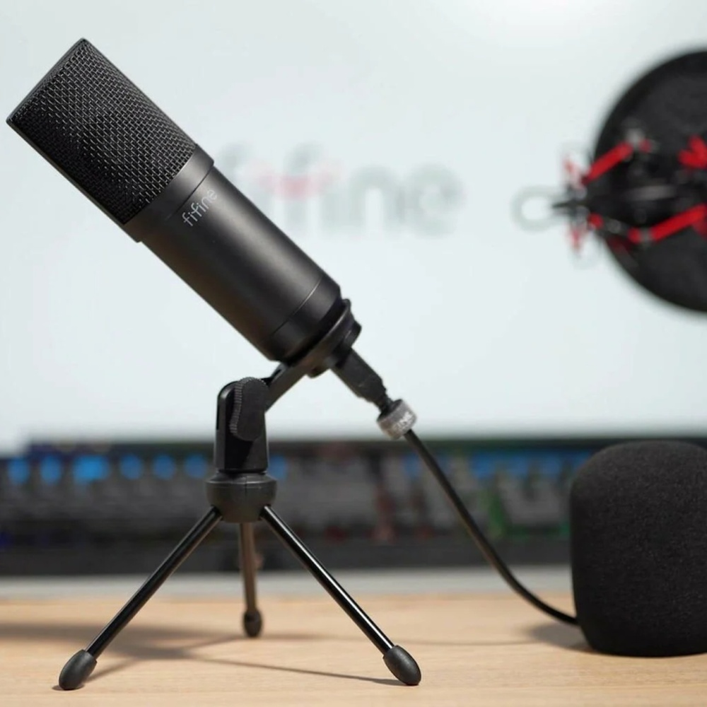 Arkada pop filtresi bulunan küçük bir tripod standında siyah kondenser mikrofon.