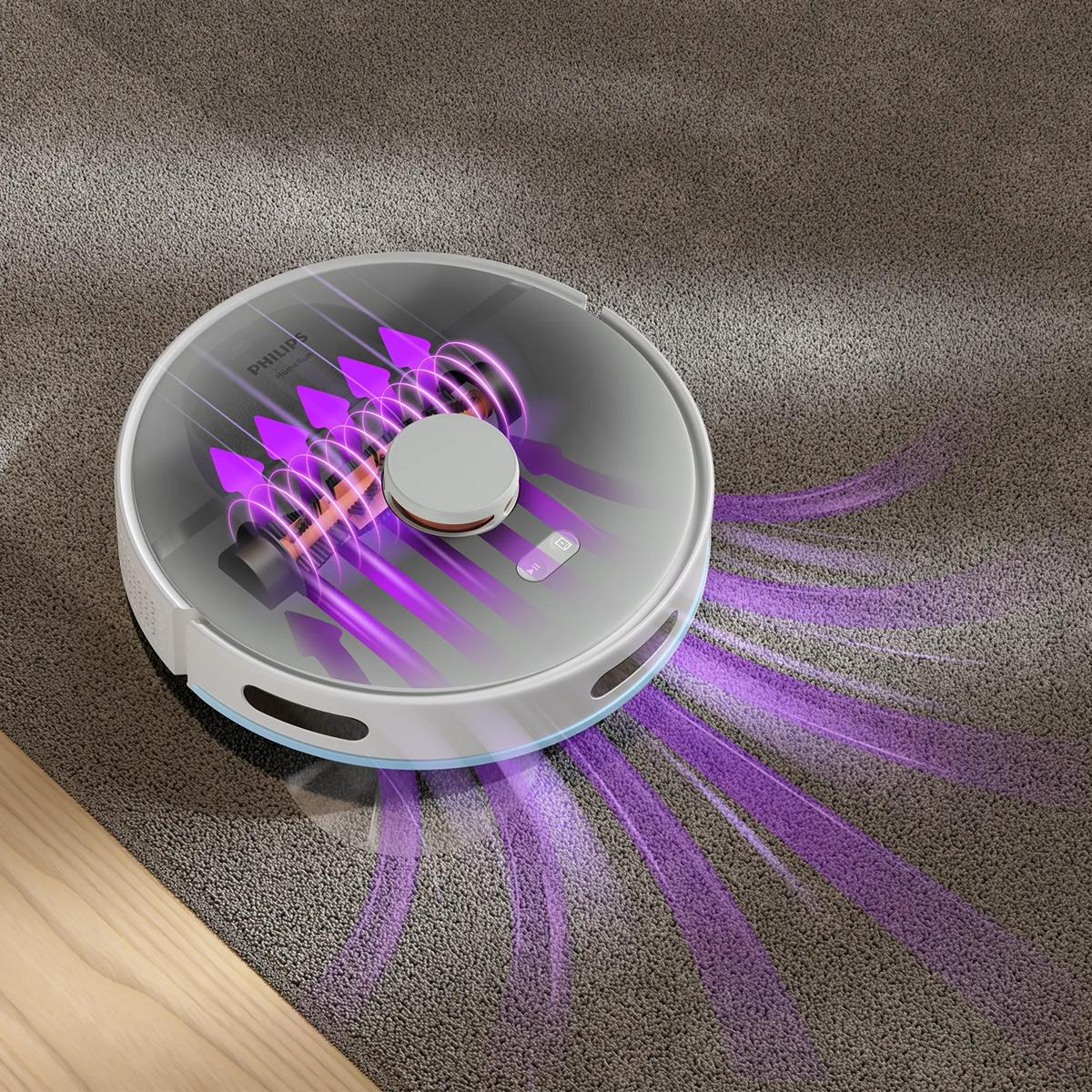 Un robot aspirador redondo succiona partículas moradas de una alfombra.