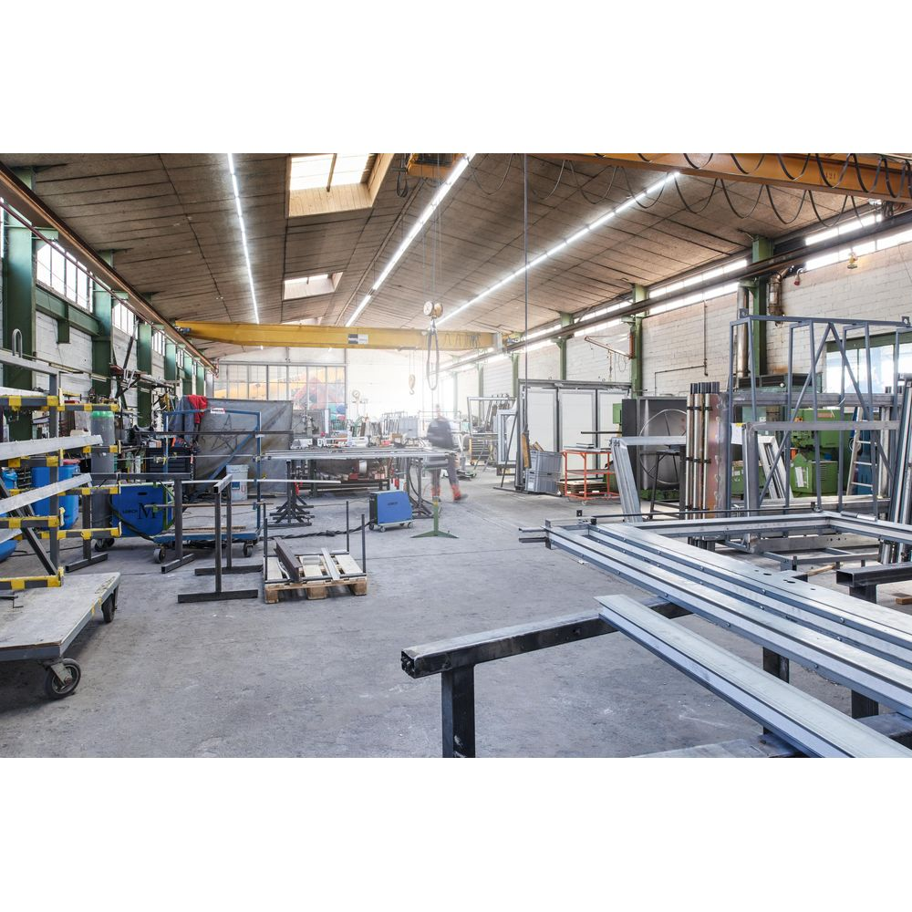 Eine Werkstatt mit Metallkonstruktionen, Werkzeugen und einem Arbeiter.
