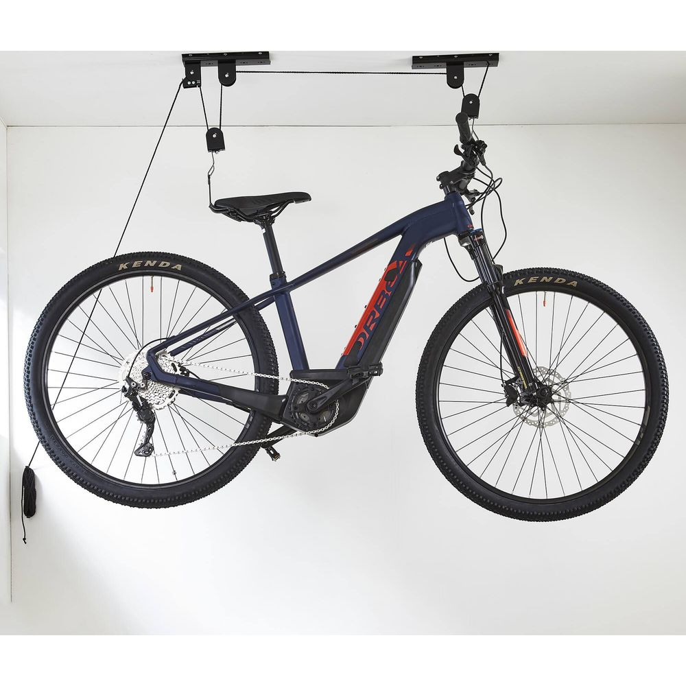 Un vélo électrique bleu foncé suspendu à un support de plafond. Il présente des accents rouges.