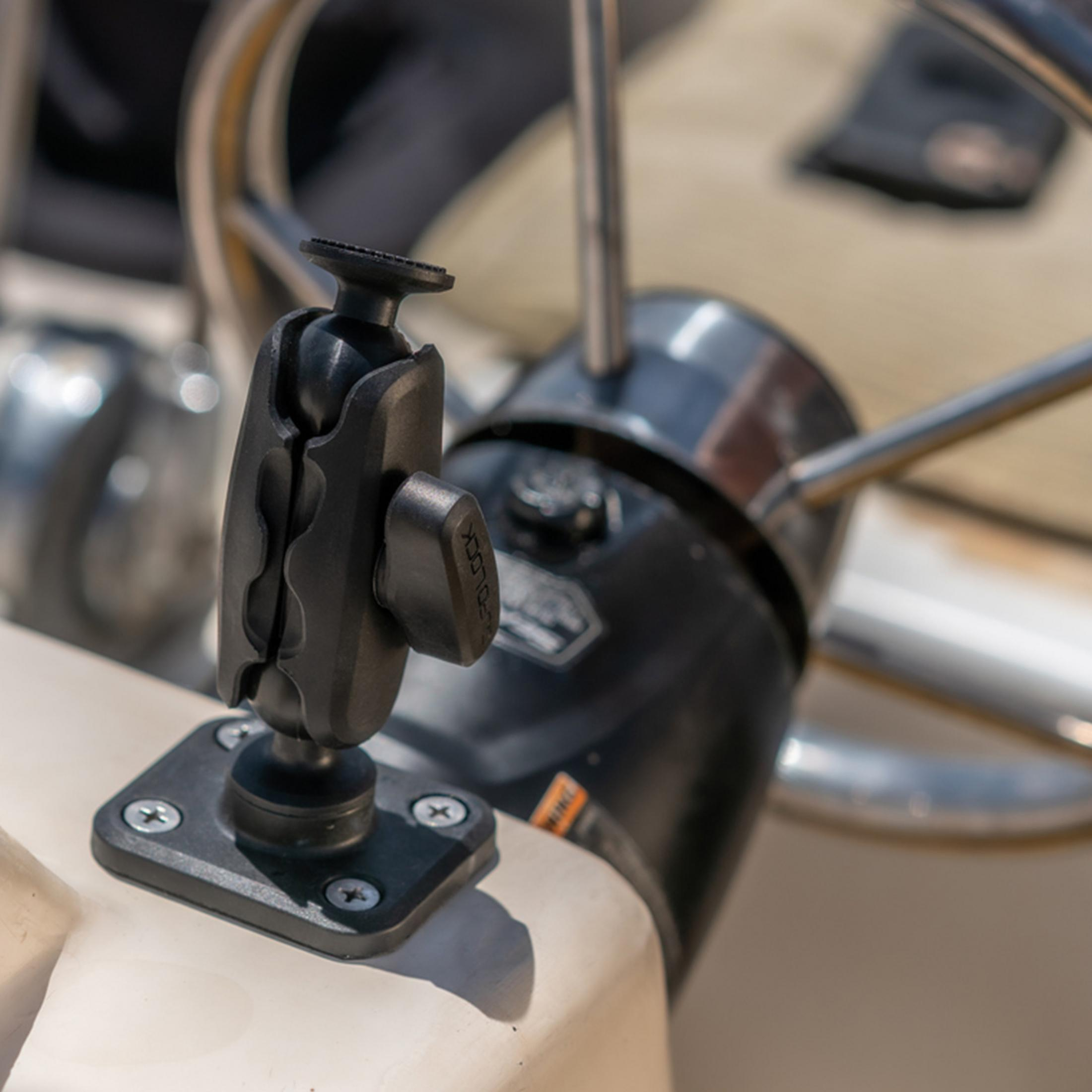 Base et bras de montage RAM noirs fixés au tableau de bord d'un bateau près du volant.