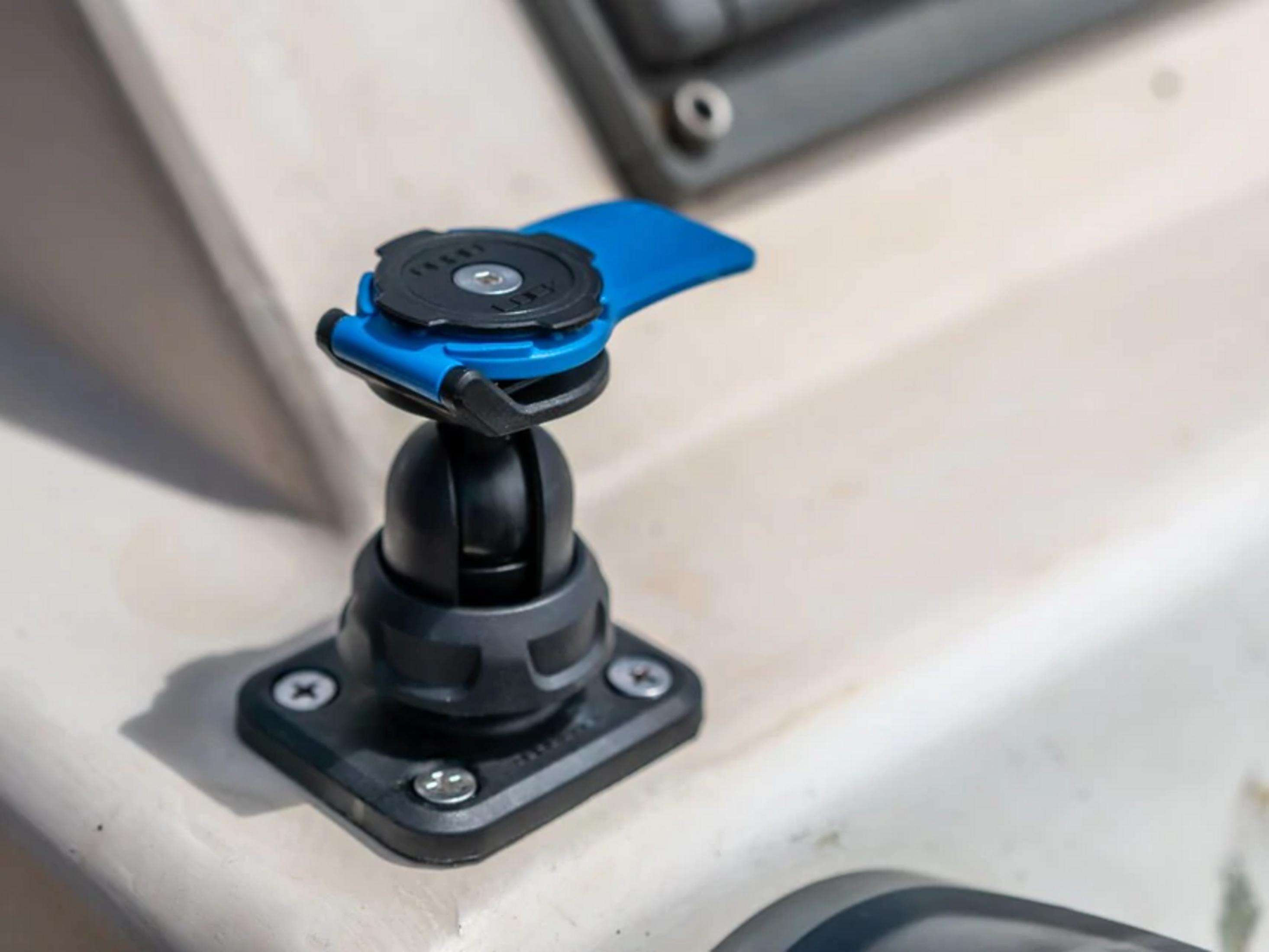 Un support noir et bleu avec rotule est vissé sur une surface de couleur claire.