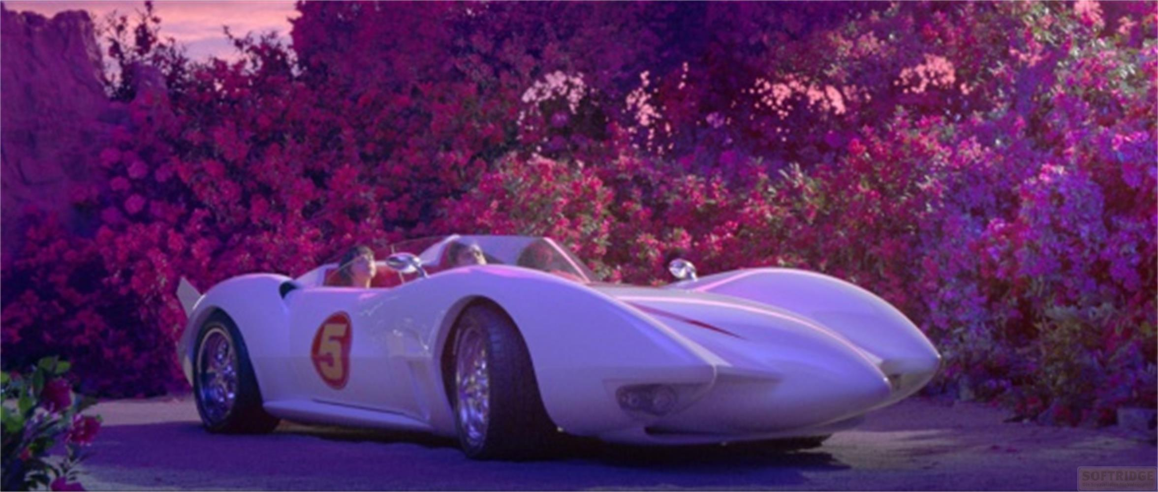 Un'auto bianca con il numero 5 attraversa un giardino fiorito.