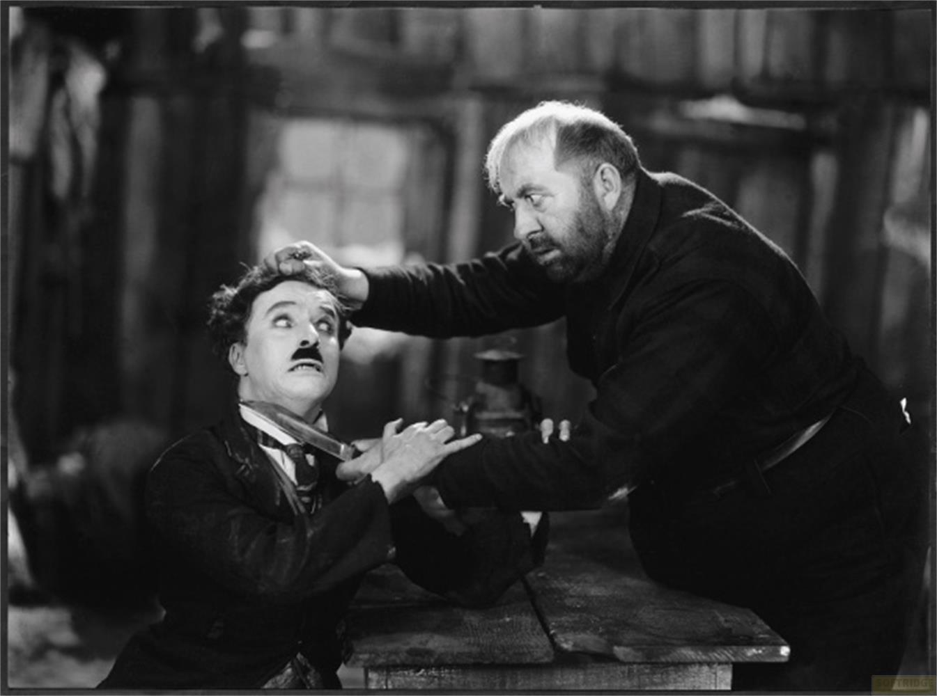 Un uomo con un coltello minaccia Charlie Chaplin, che si ritrae spaventato.