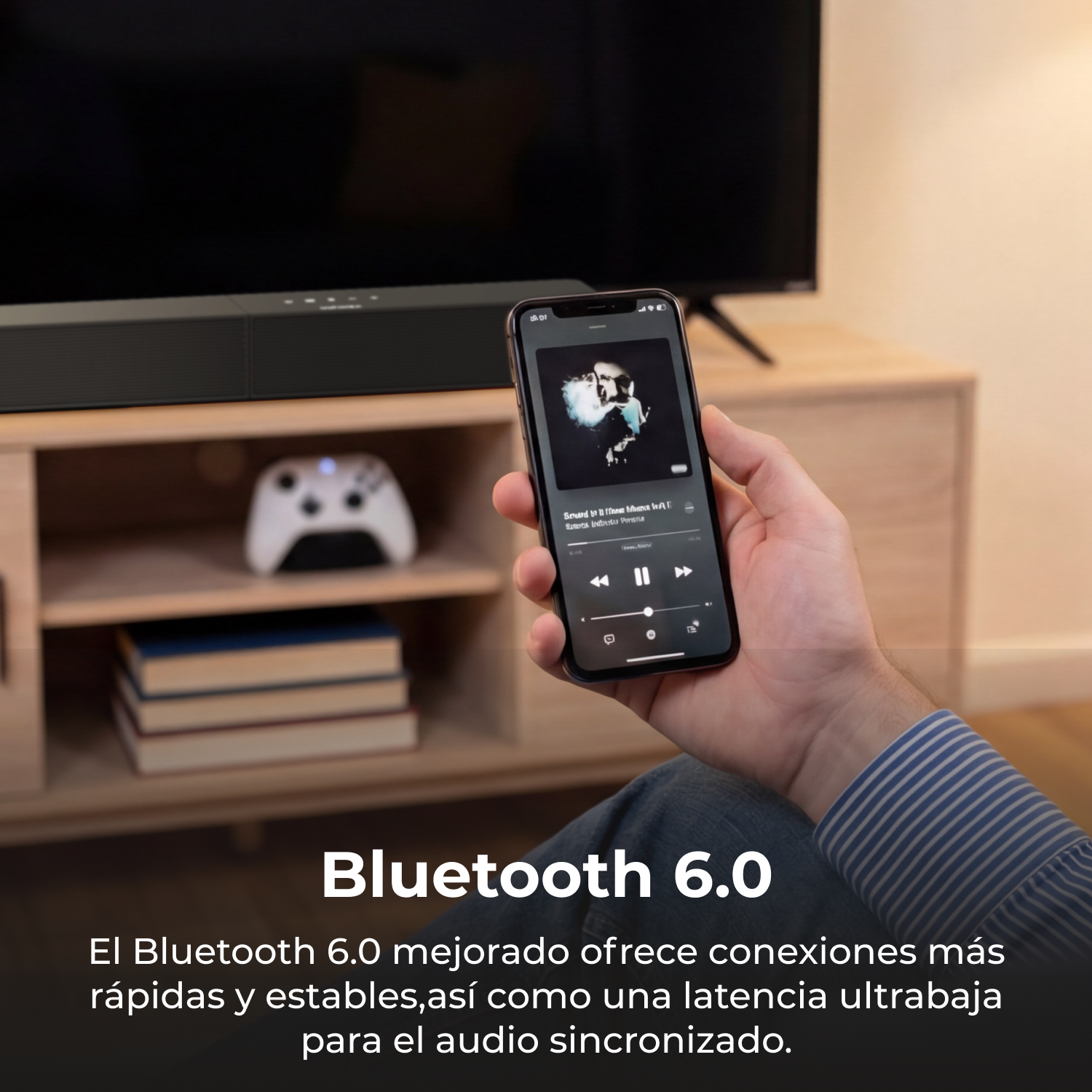Un hombre sostiene un smartphone con app de música frente a barra de sonido, TV y mando.
