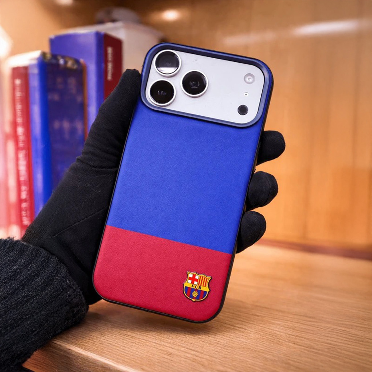 Un teléfono con funda azul y roja con logo FCB en la mano.