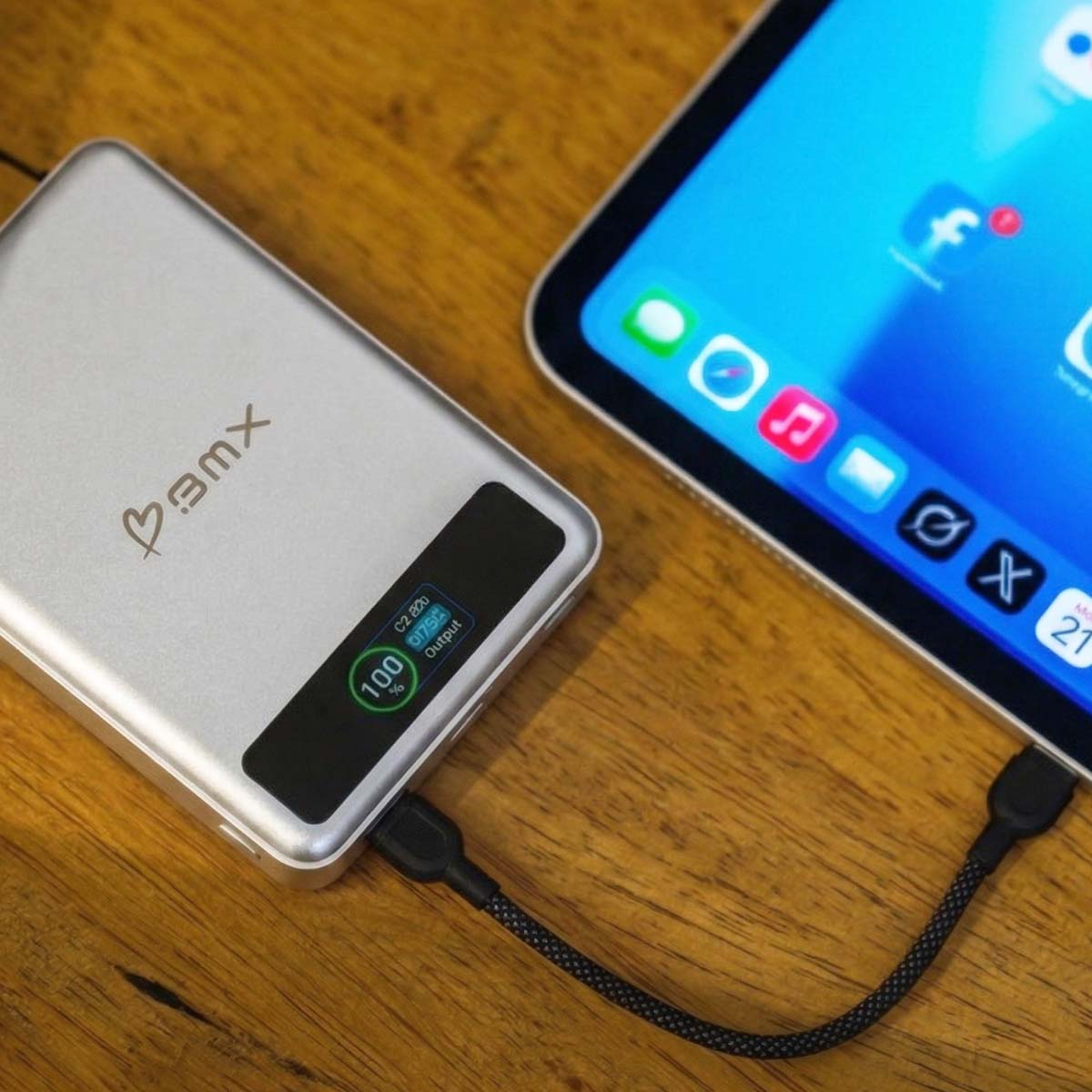Eine silberne Powerbank mit 100% Ladeanzeige, verbunden mit einem Tablet.