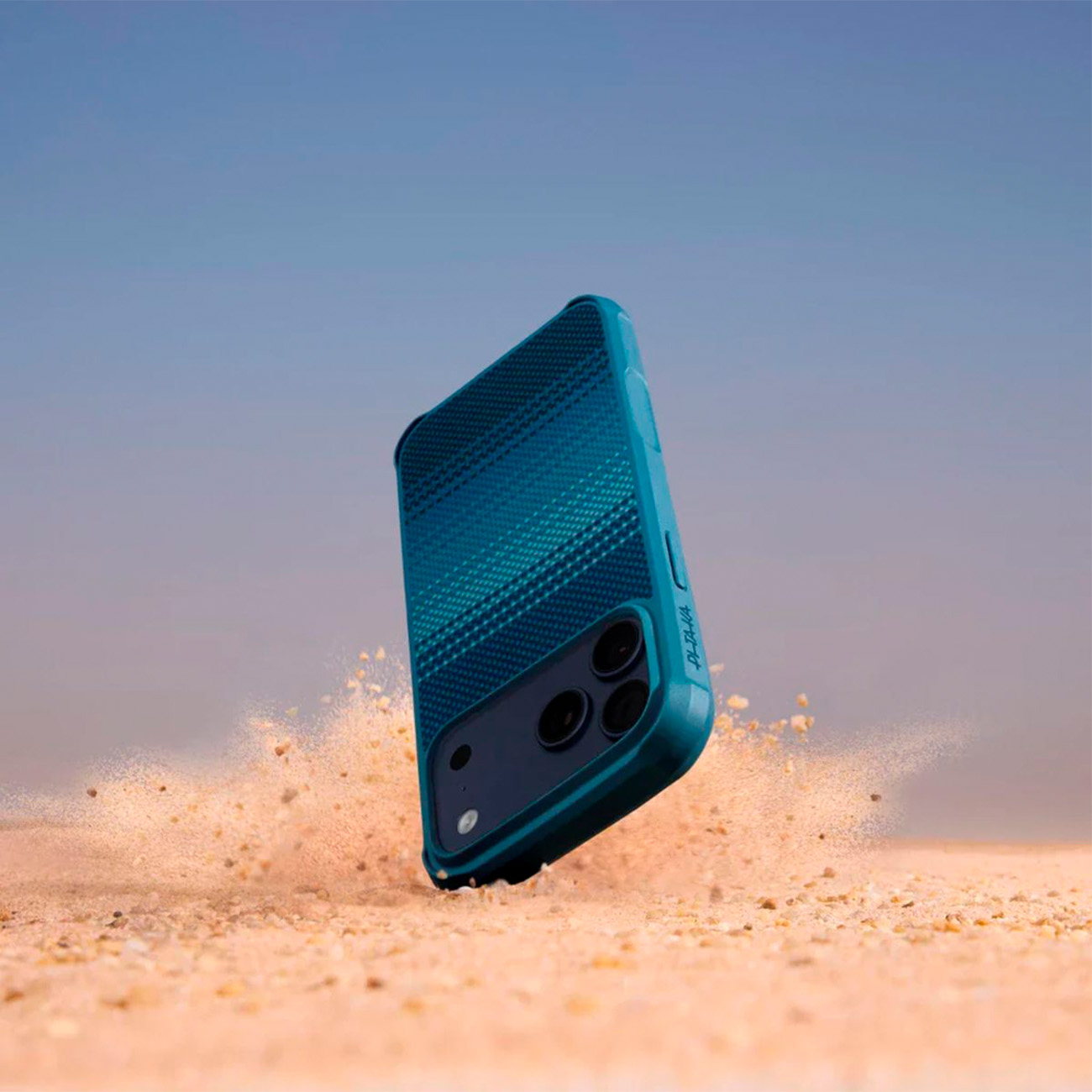 Una custodia blu per telefono vola sulla sabbia, con cielo blu sullo sfondo.
