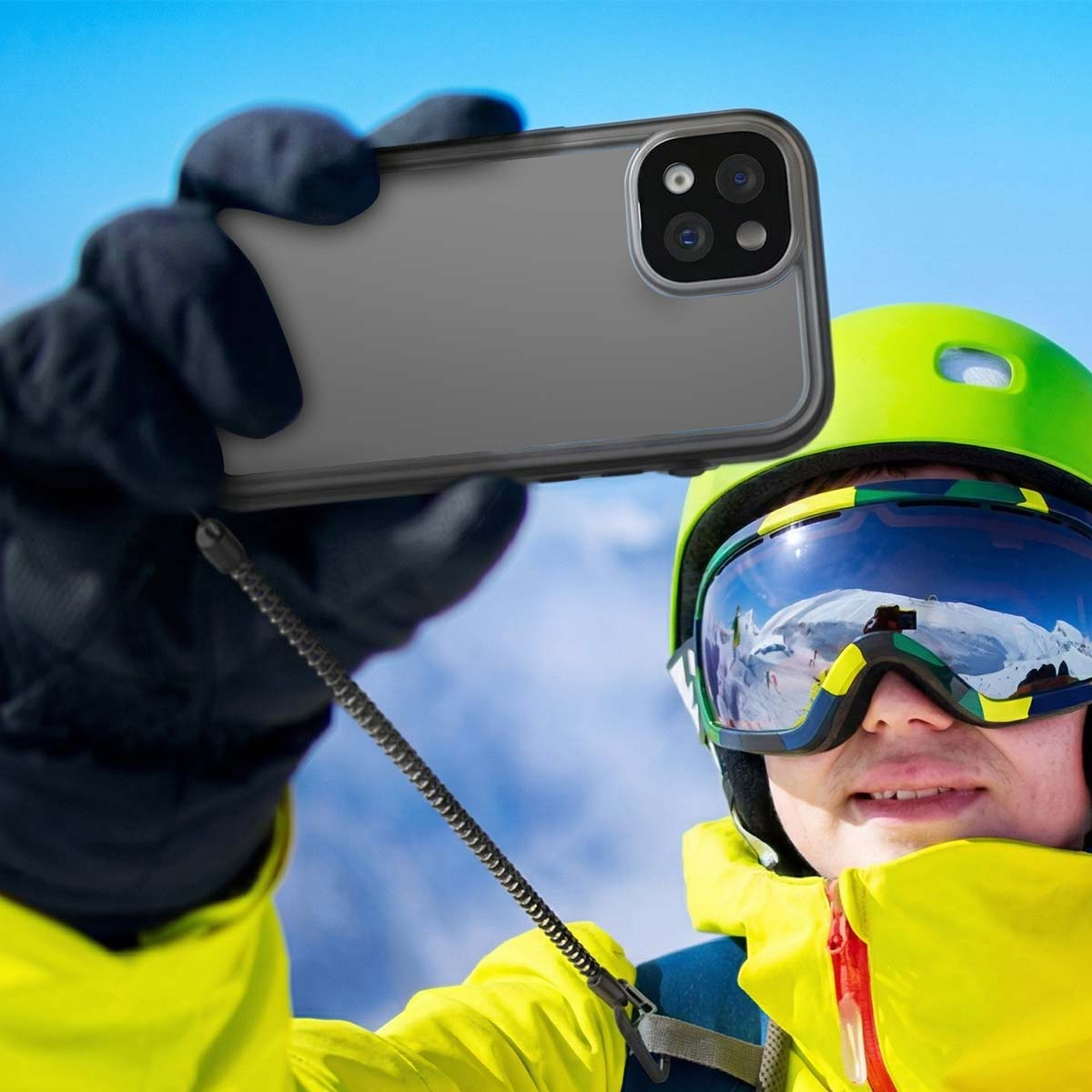 Een skiër in een gele jas en helm maakt een selfie met zijn smartphone.