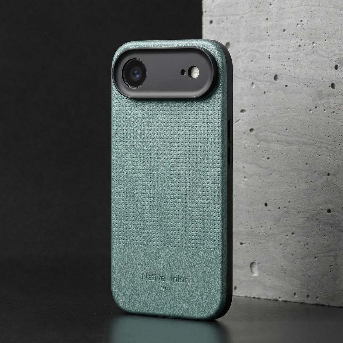 Custodia verde per telefono con motivo perforato e ritaglio fotocamera su sfondo grigio.