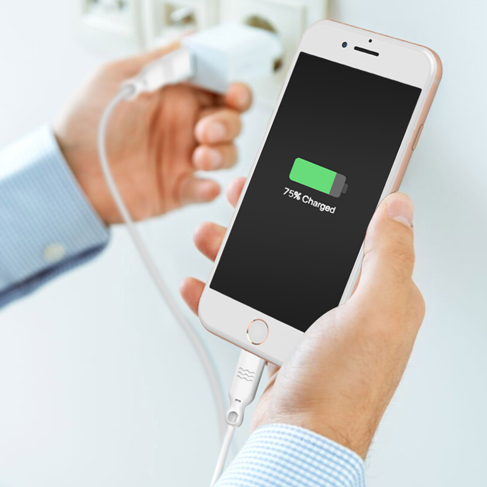 Hände laden ein weißes Smartphone mit einem Stecker in eine Steckdose.