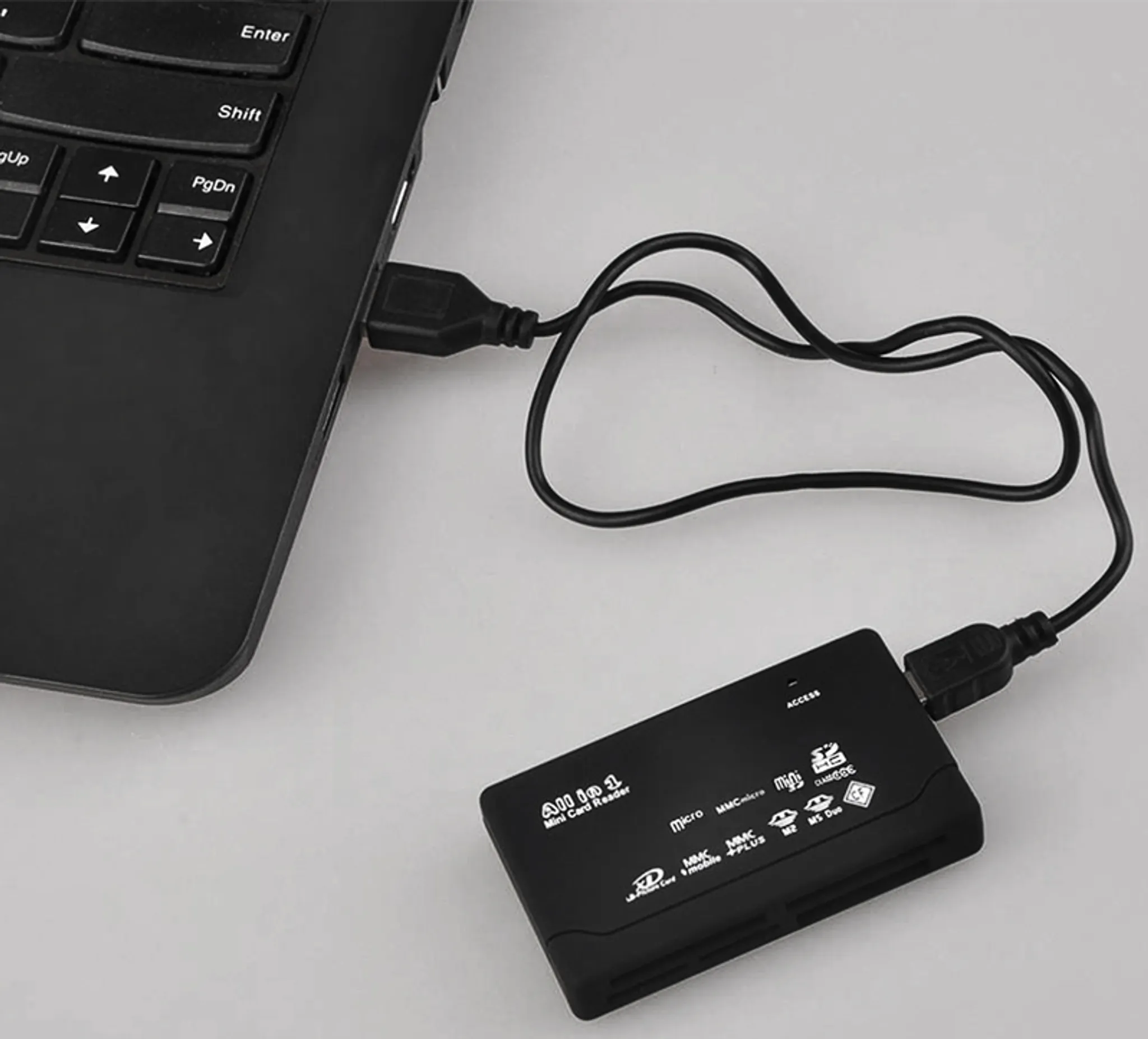 Ein schwarzer Kartenleser ist über ein USB-Kabel mit einem schwarzen Laptop verbunden.
