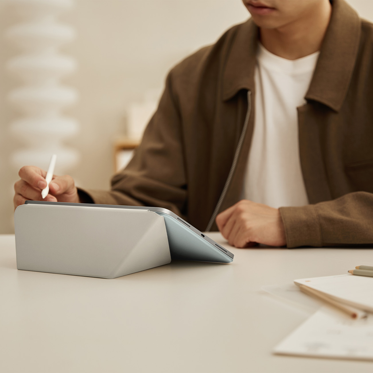 Hombre con tableta y lápiz en escritorio con cuadernos.