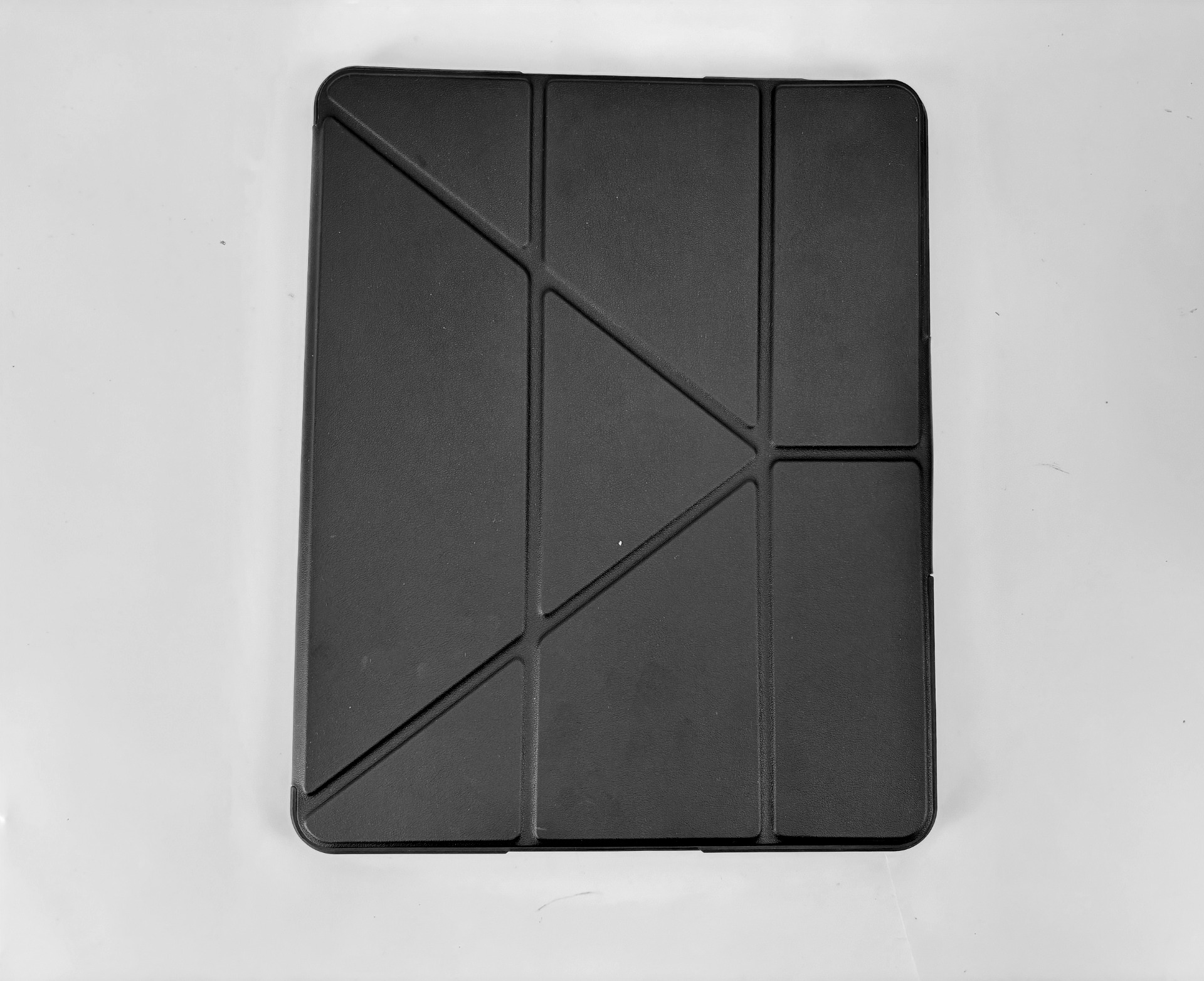 Una custodia nera piegata per tablet su sfondo bianco.