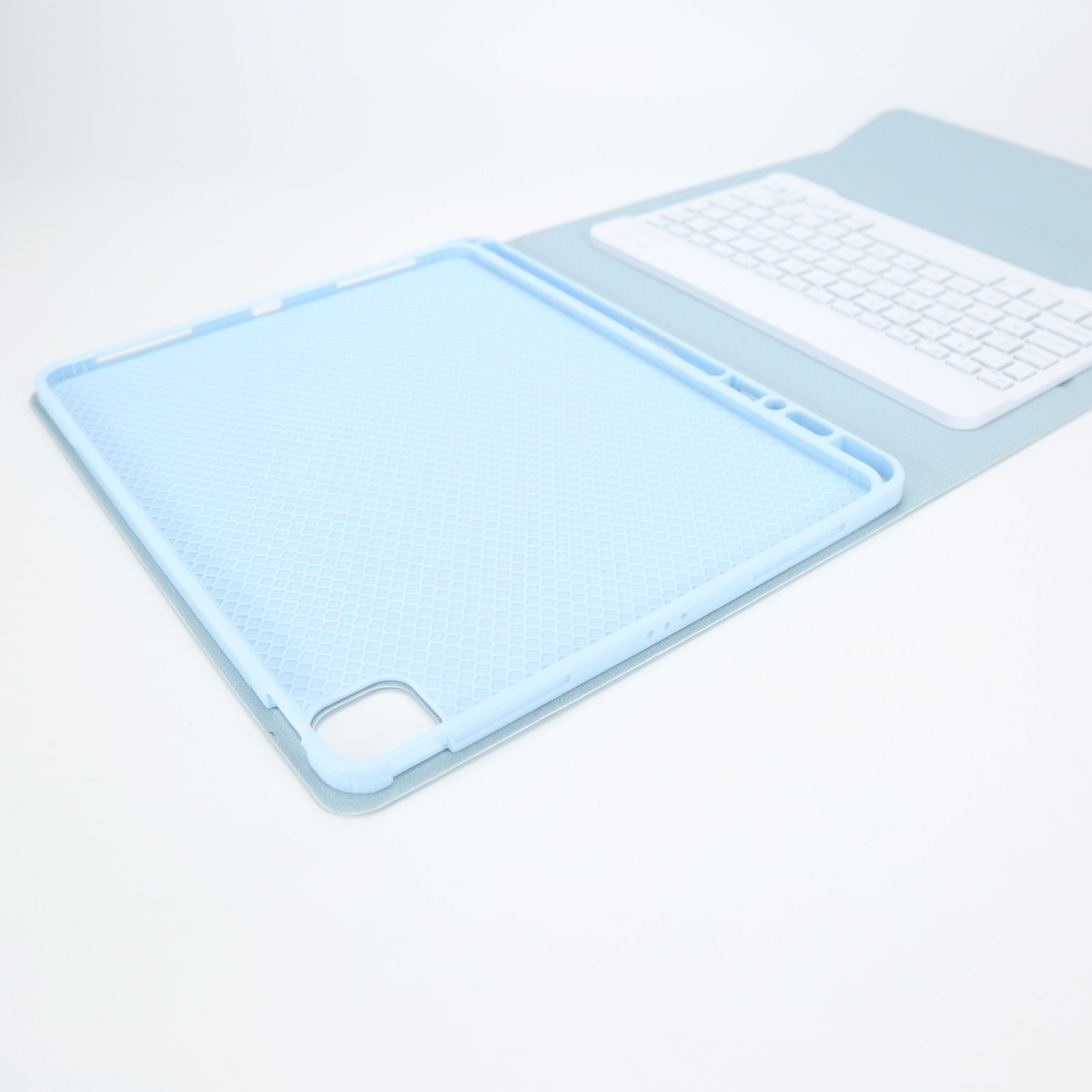 Lichtblauwe tabletcase met honingraatpatroon en wit toetsenbord op lichte achtergrond.