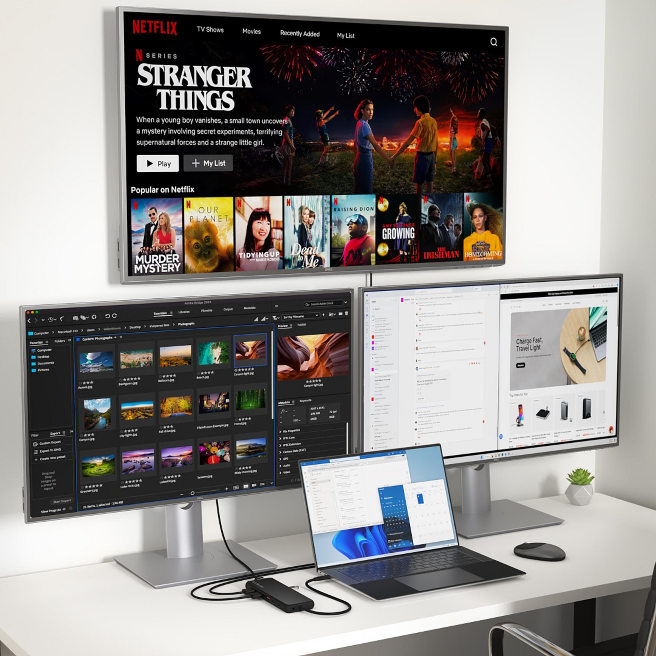 Ein Schreibtisch mit drei Monitoren, einem Laptop und einem Netzteil.