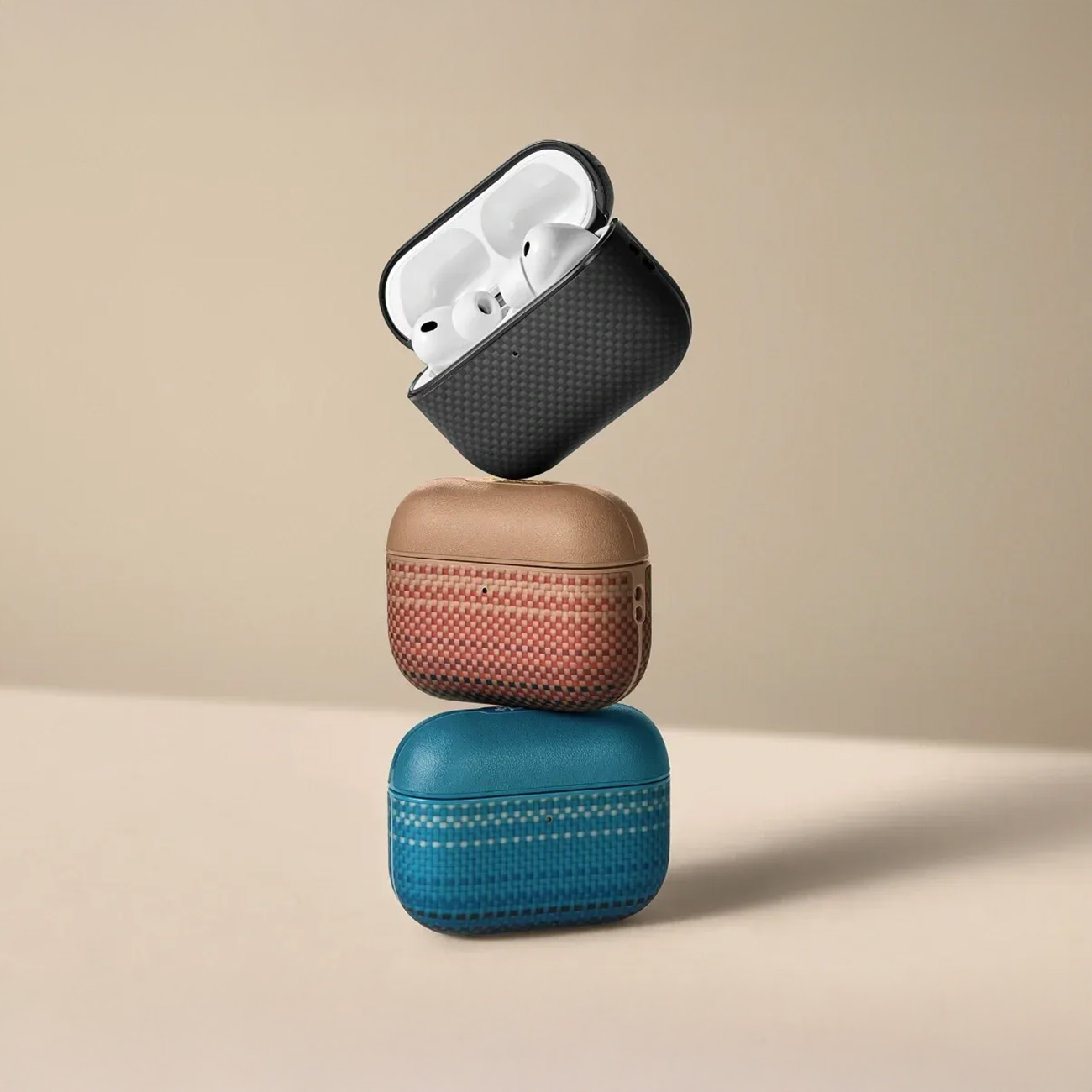 Tres estuches de auriculares apilados: fibra de carbono negra, texturizado beige, tejido azul.