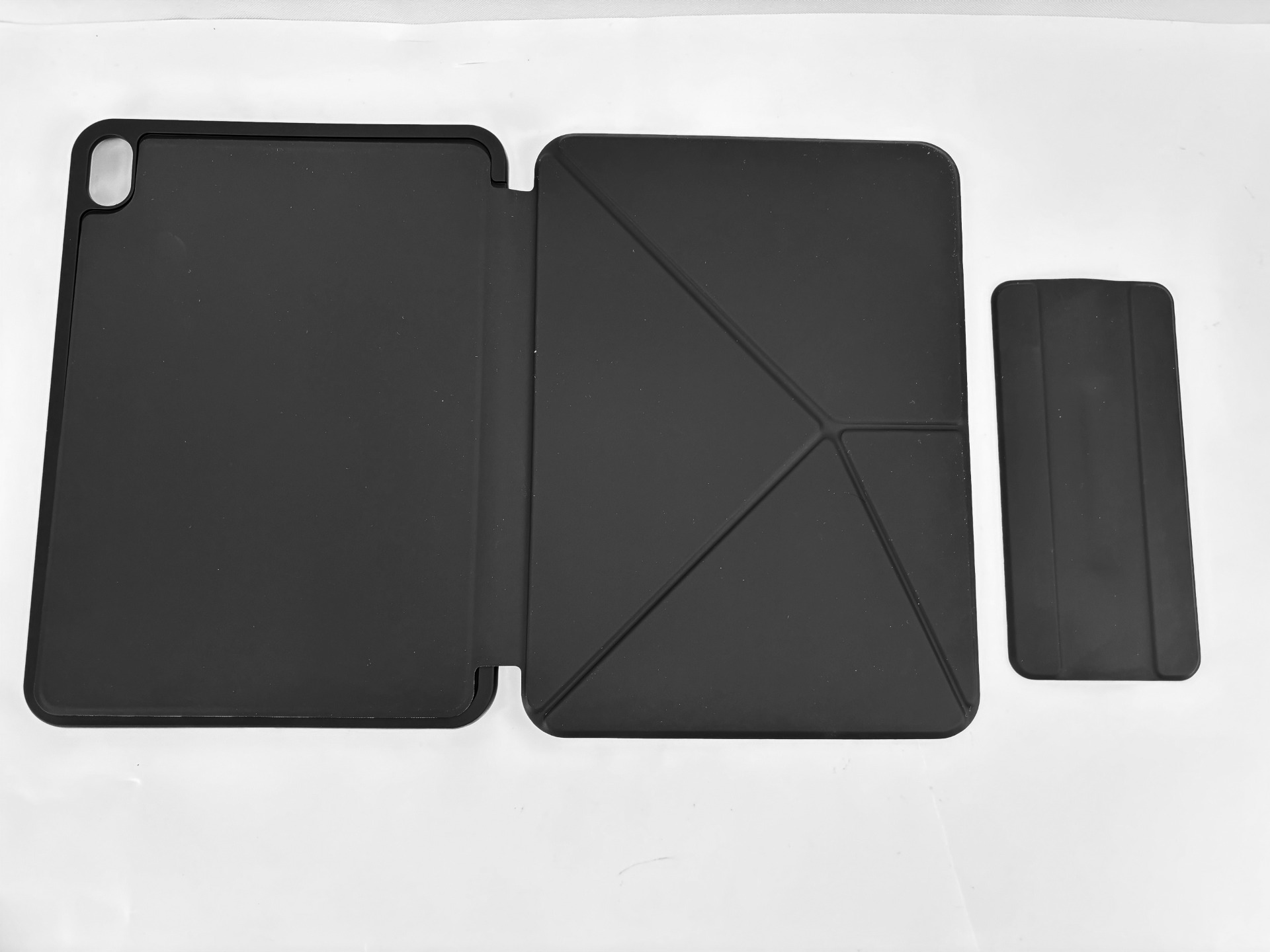 Una custodia nera per tablet giace aperta su una superficie bianca.