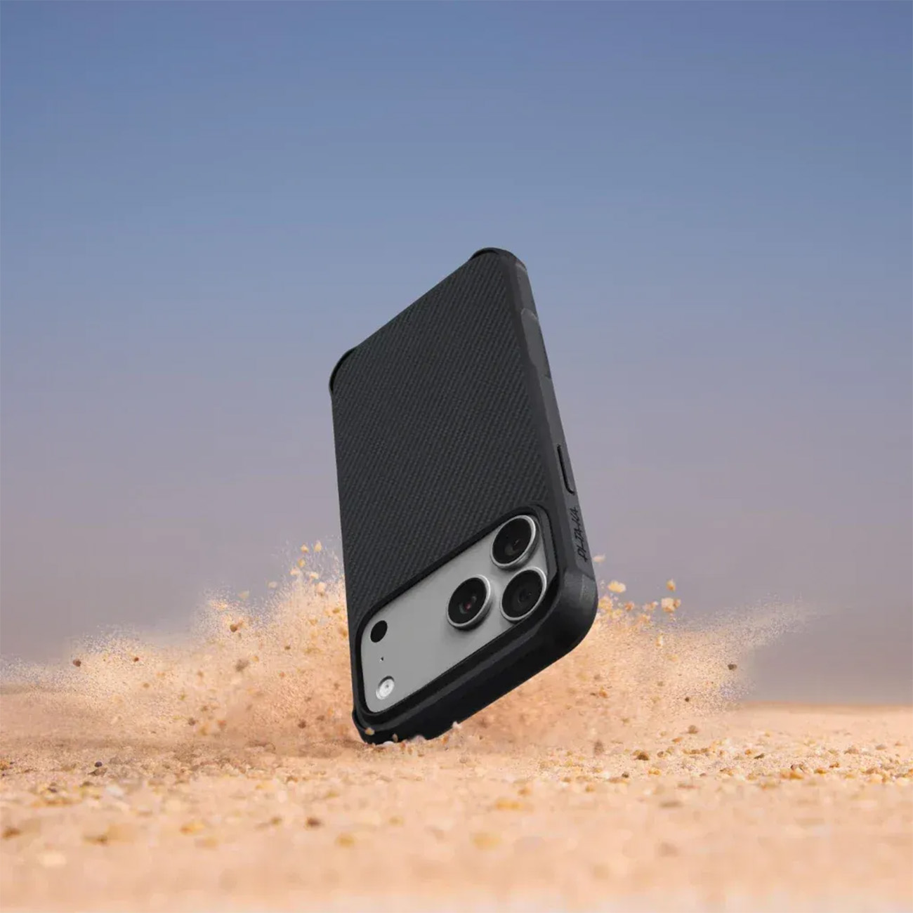 Schwarzes Handy mit Kamerasystem landet im Sand.