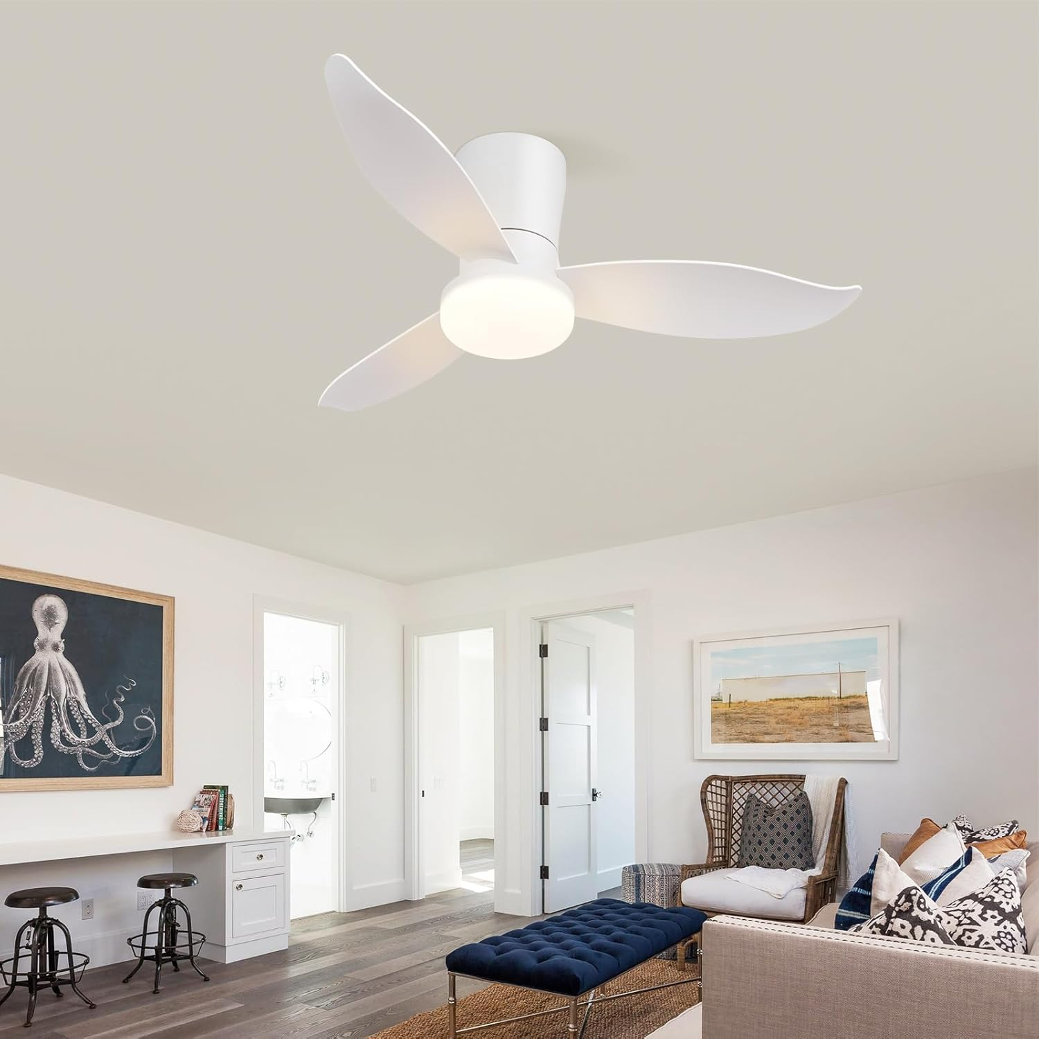 Un ventilatore da soffitto bianco con luce in un soggiorno accanto a una scrivania con arte.